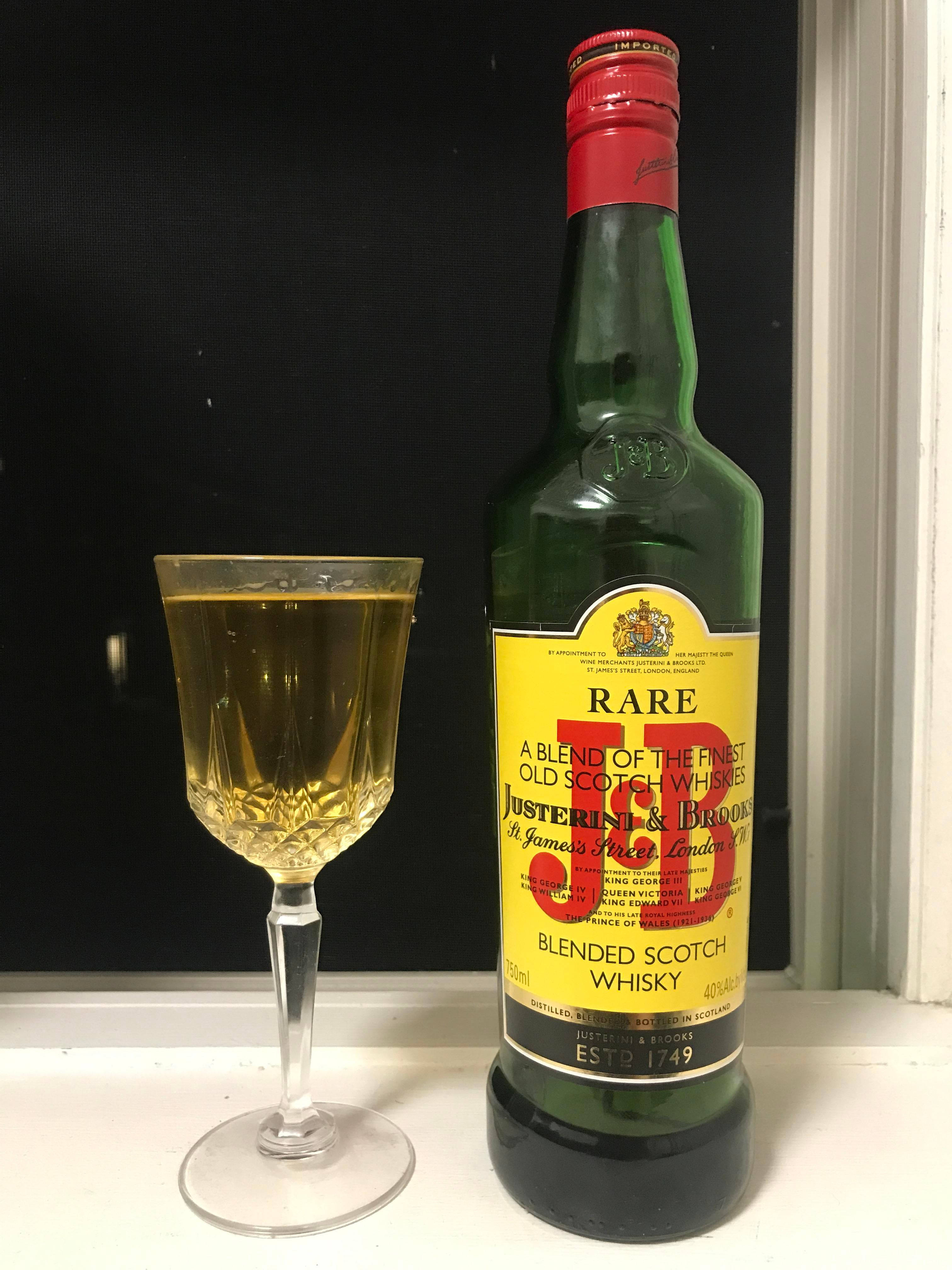 drinks 桌布 壁紙 — 一瓶綠色J D Rare Blended Scotch Whisky立於白色窗台上，旁邊放著一個裝滿金色威士忌的水晶杯，背景為深色。