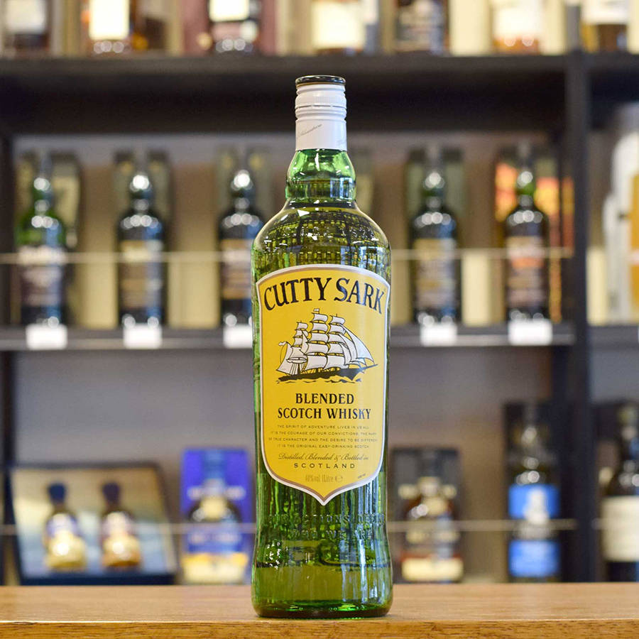 alcohol 桌布 壁紙 — 一瓶綠色玻璃瓶裝的Cutty Sark調和蘇格蘭威士忌放在木製吧檯中央，背景中其他酒瓶的架子模糊不清。