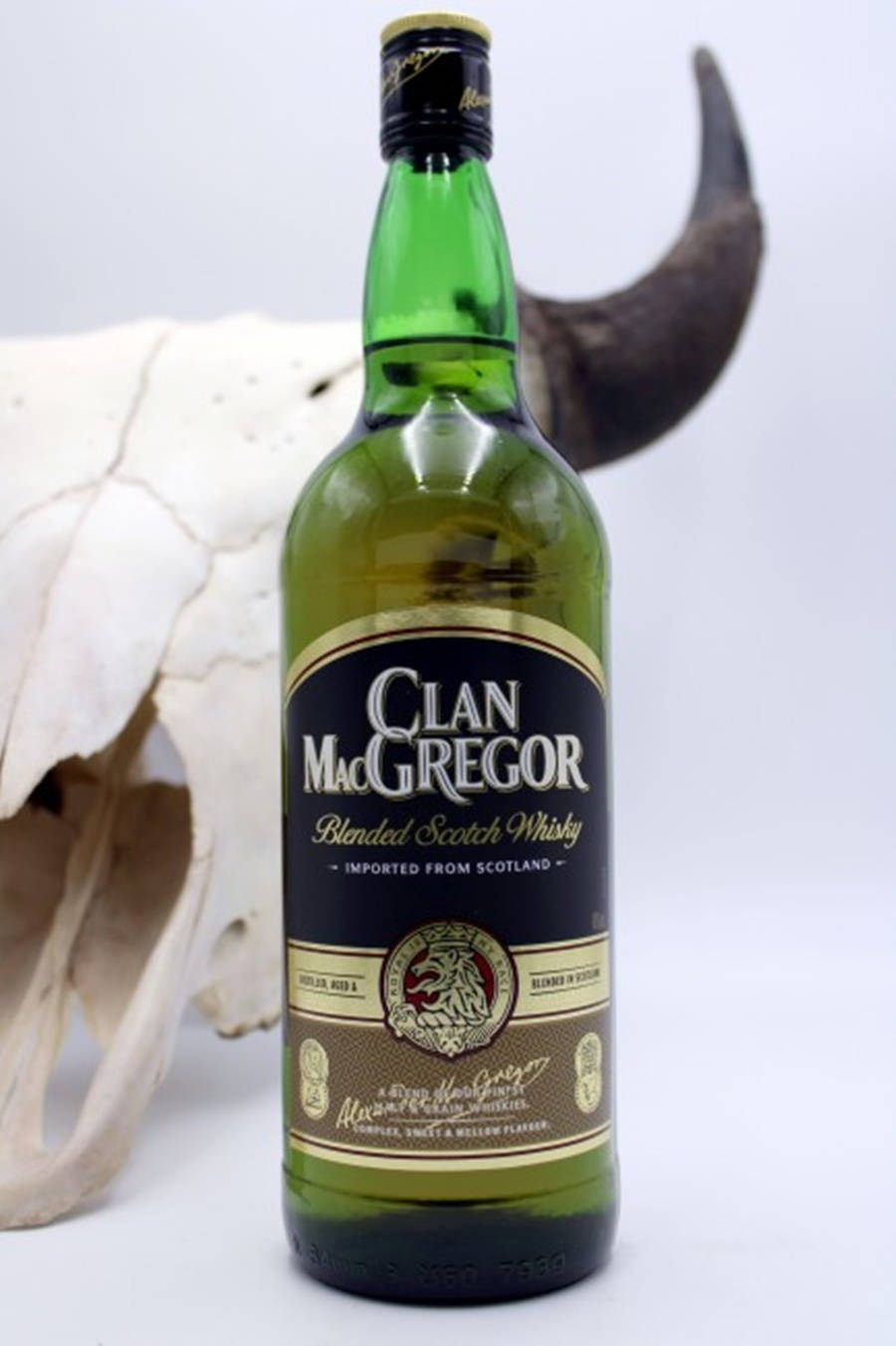 Whiskey 桌布 壁紙 — 一瓶綠色的 Clan MacGregor 調和蘇格蘭威士忌，在純白背景中央，旁邊有一個大動物頭骨和角。