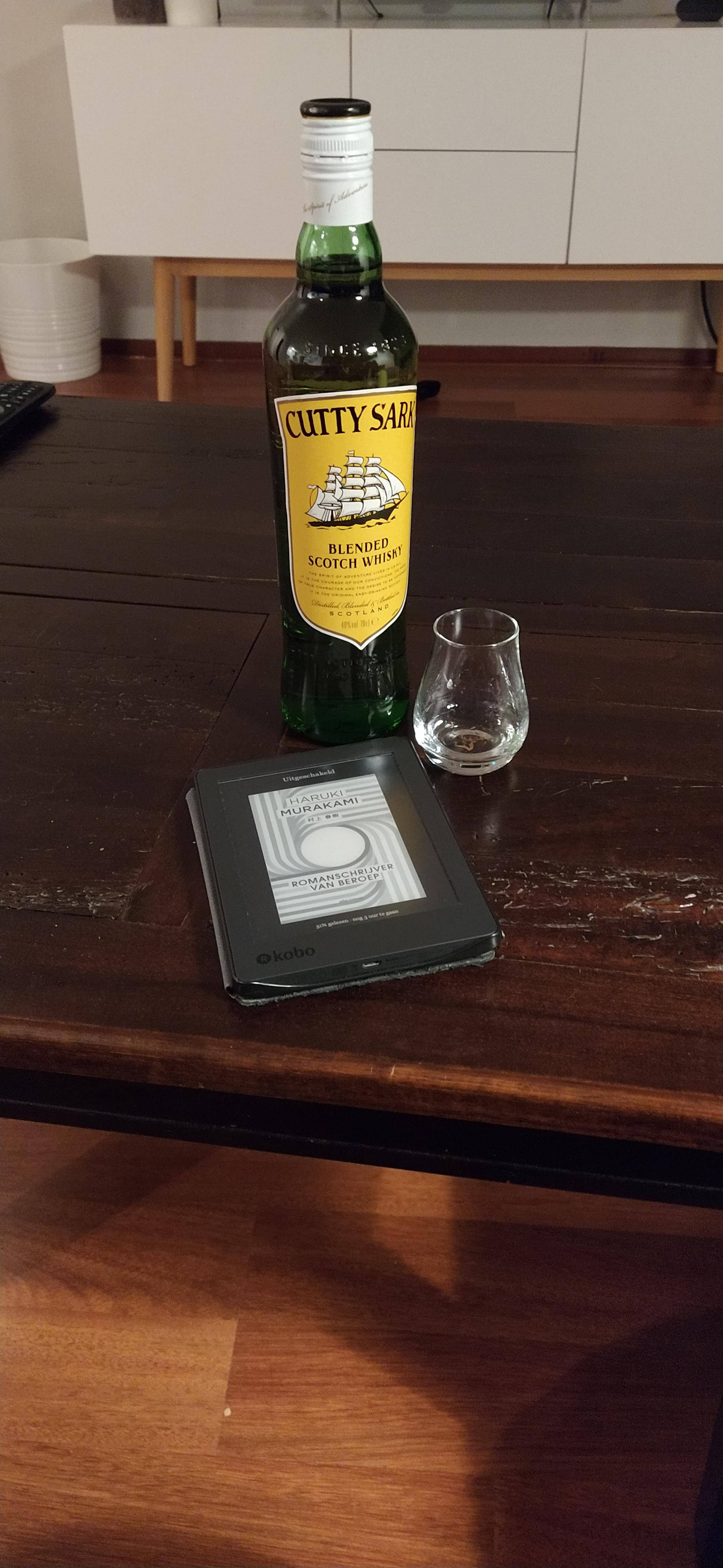 bottle 桌布 壁紙 — 一瓶綠色的 Cutty Sark 威士忌和一個空杯放在一部電子書閱讀器旁邊，在一張深色木桌上。