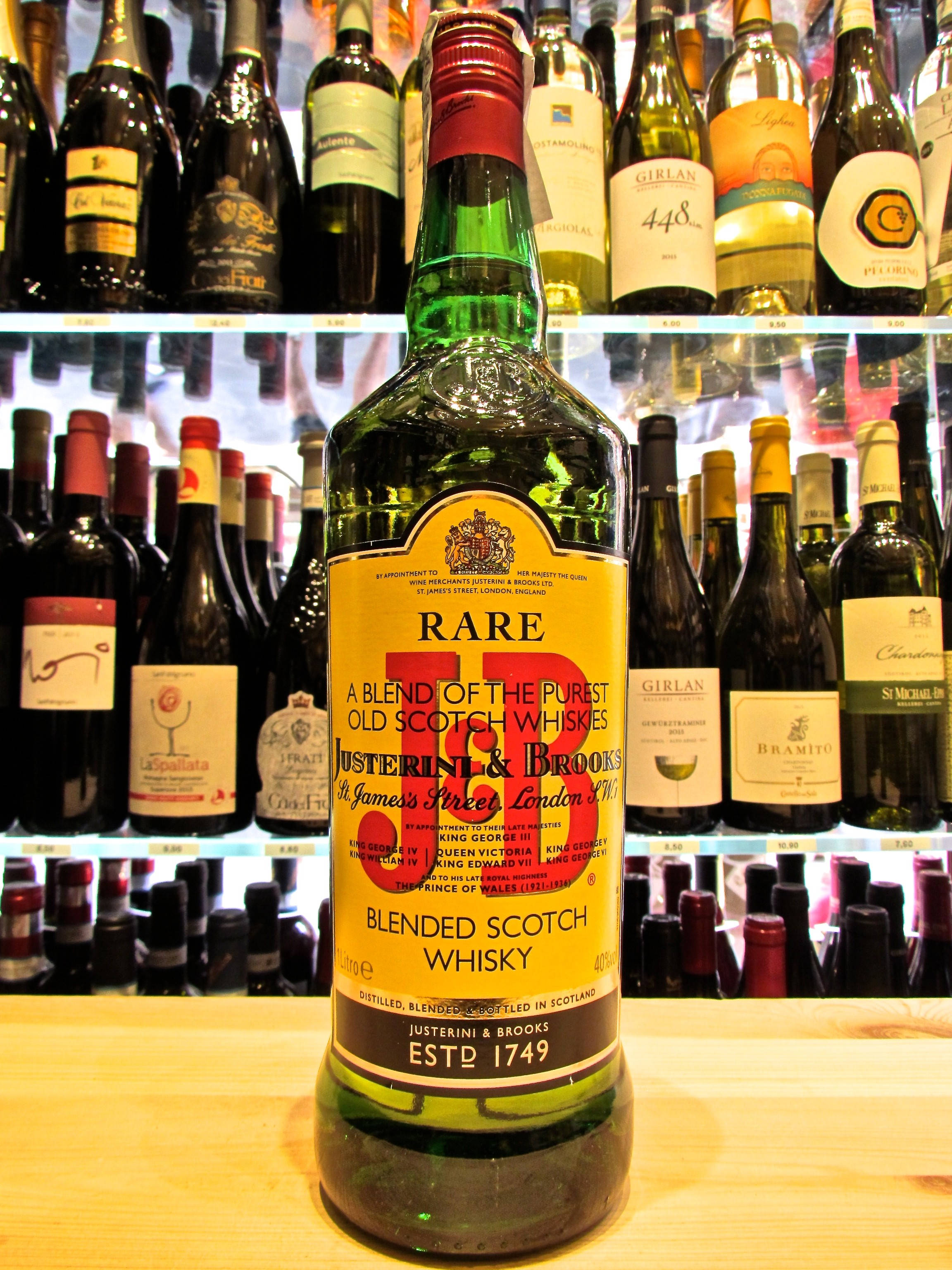 drinks 桌布 壁紙 — 一瓶綠色的Justerini & Brooks Rare Blended Scotch Whisky醒目地放在木製櫃檯上，後面有擺滿酒瓶的架子。