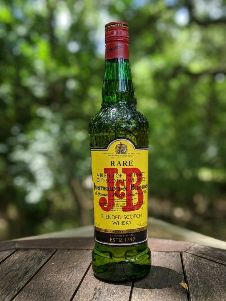 drinks 桌布 壁紙 — 一瓶綠色的Justerini & Brooks Rare Old Blended Scotch Whisky放在一張風化的木桌上，背景是柔和的綠色森林。