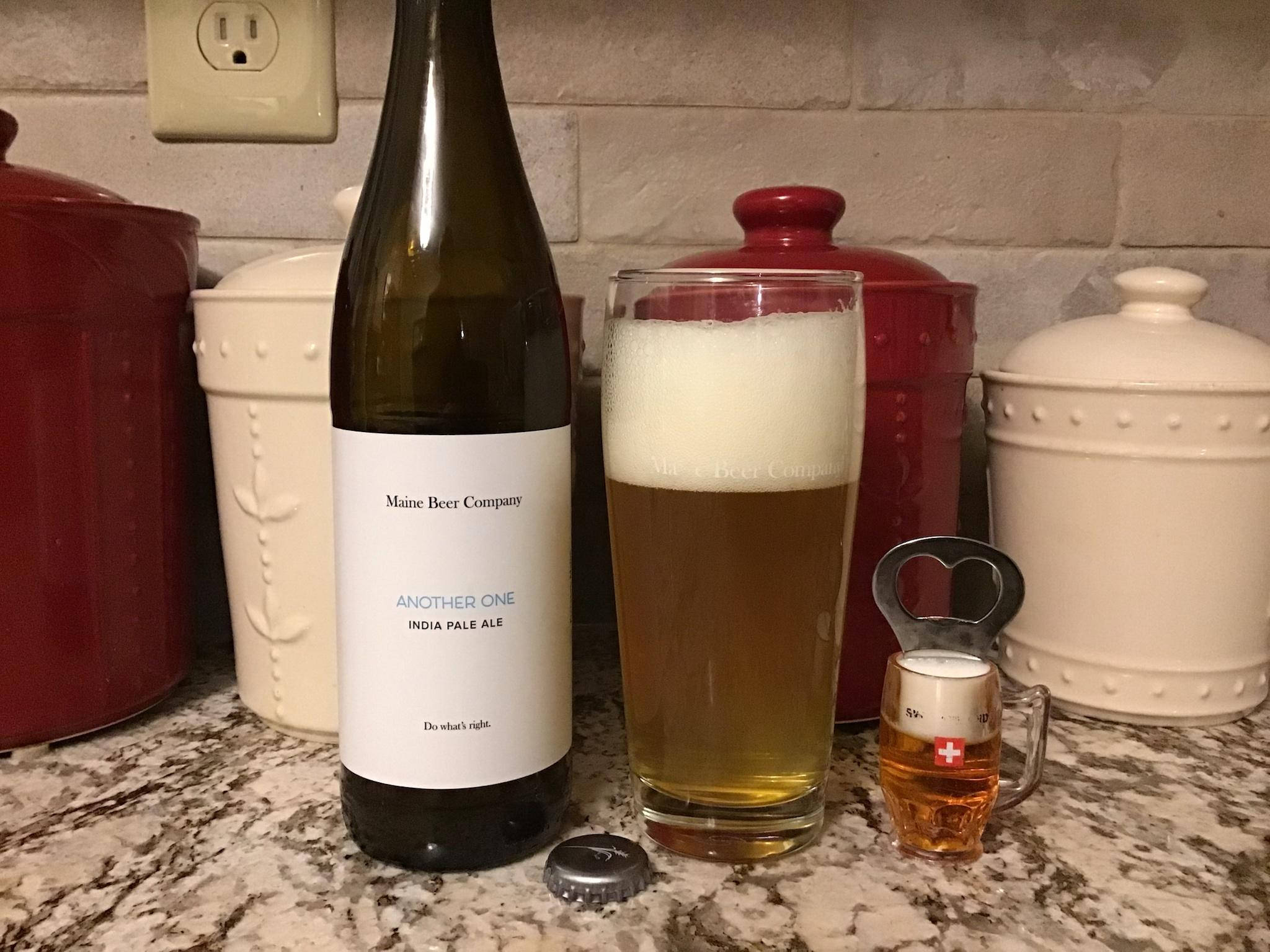 glass 桌布 壁紙 — 一瓶緬因啤酒公司印度淡色艾爾啤酒放在花崗岩檯面上，旁邊有一個裝滿泡沫啤酒的高腳杯和一個小馬克杯。