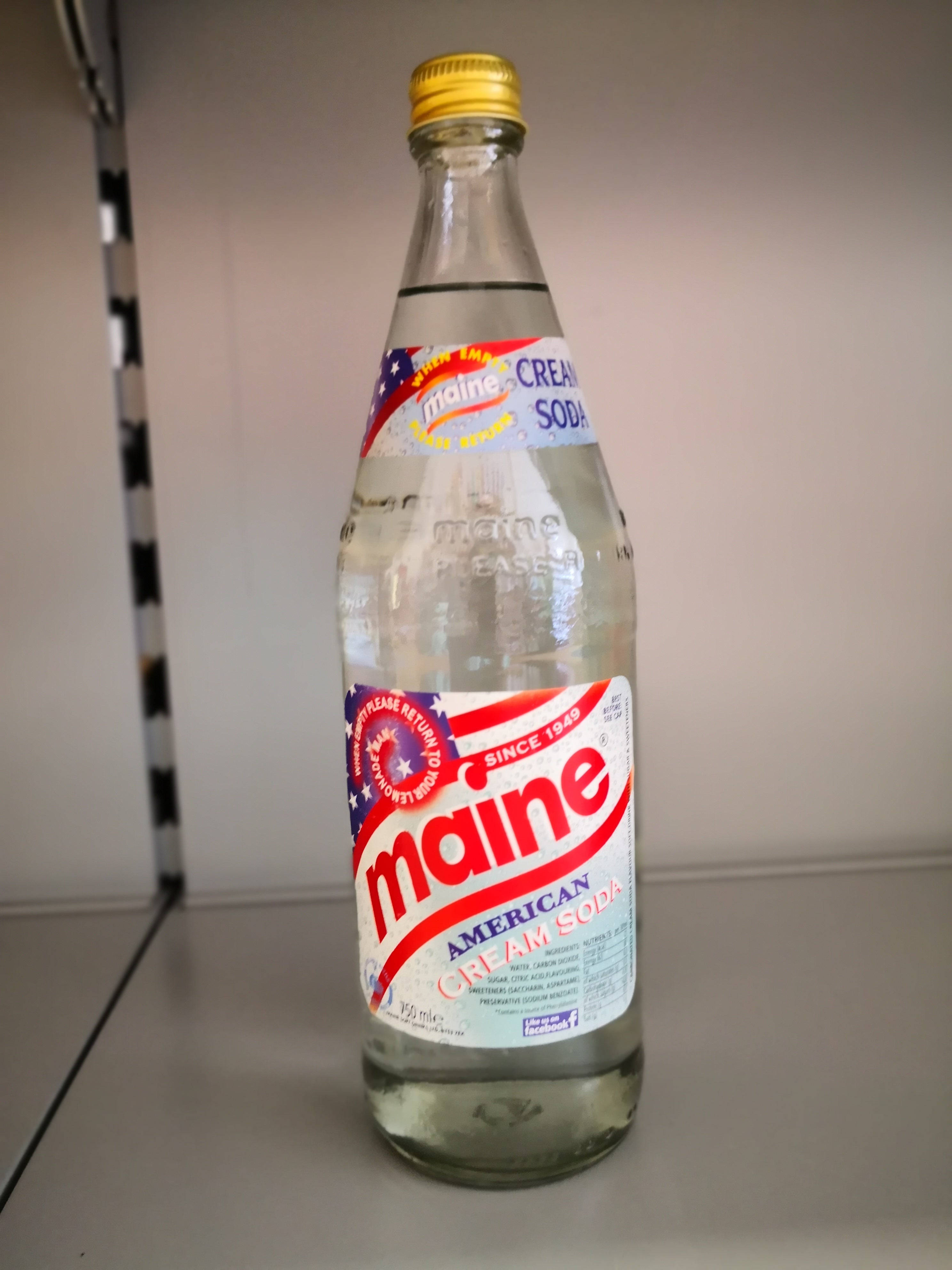 Drink 桌布 壁紙 — 一瓶緬因美式奶油蘇打水的復古玻璃瓶（金色瓶蓋）放在架子上，靠著素牆。