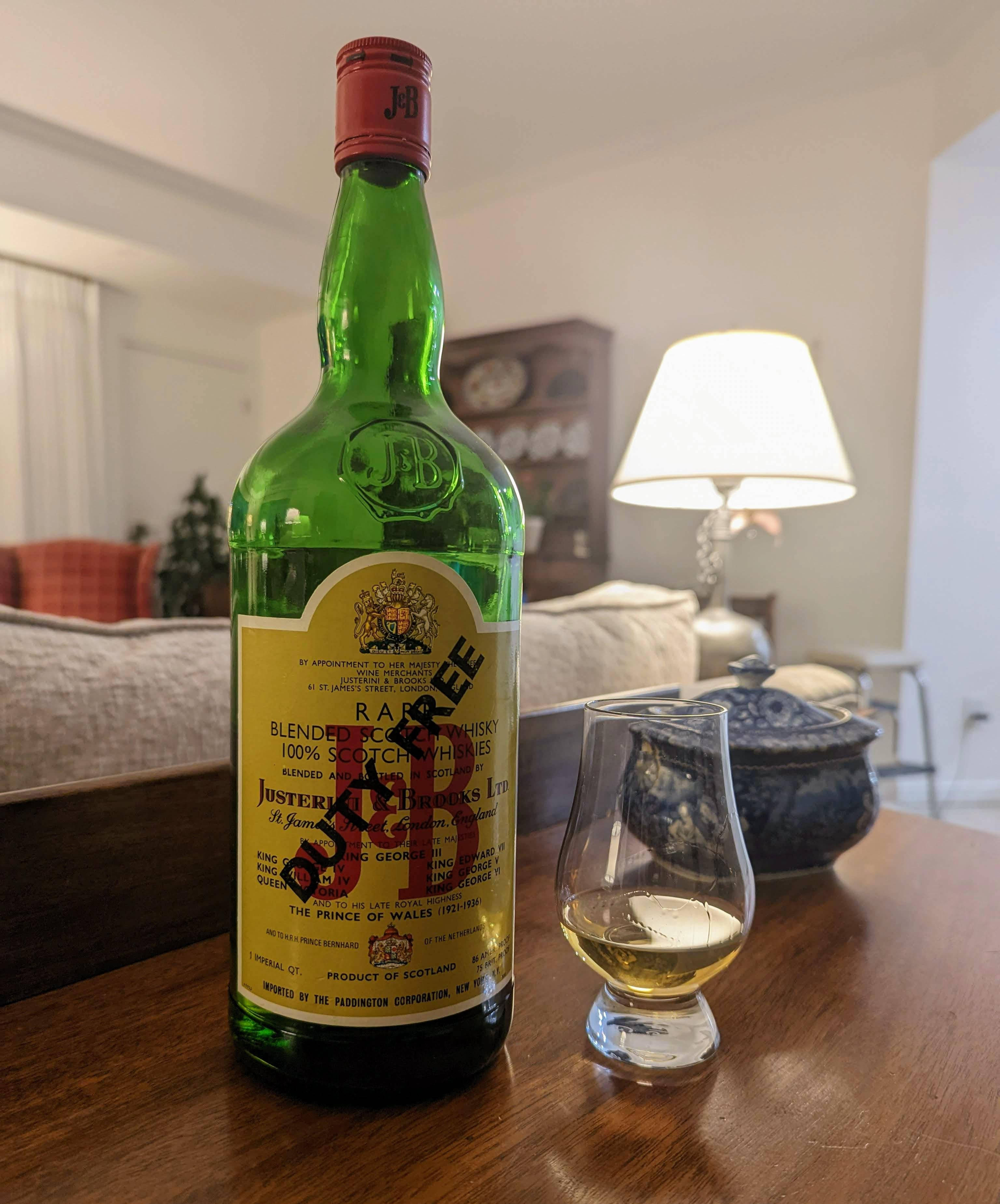 drinks 桌布 壁紙 — 一瓶罕見的調和蘇格蘭威士忌綠色酒瓶放在溫暖照明的客廳木桌上，旁邊有一個品酒杯。