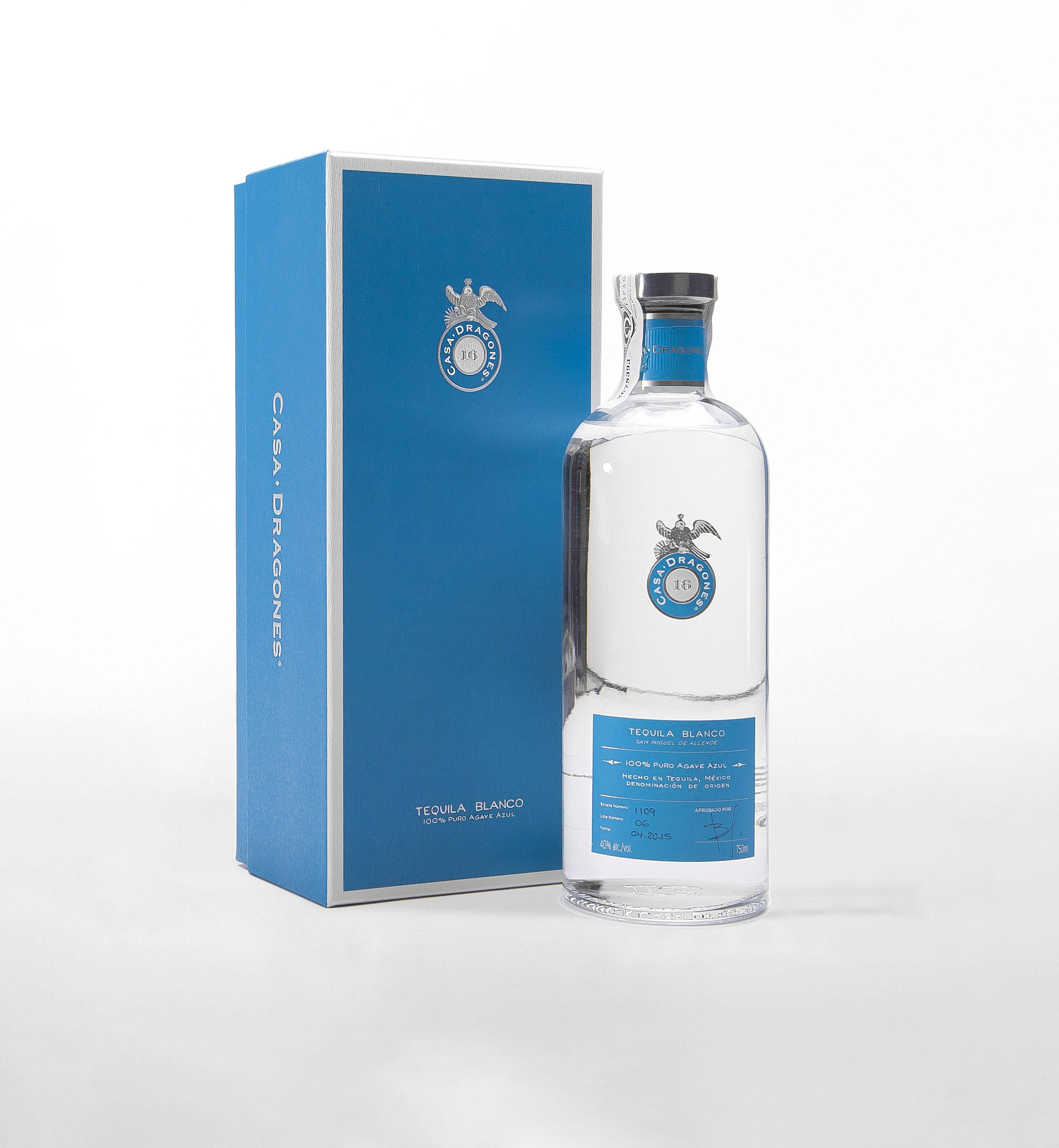 alcohol 桌布 壁紙 — 一瓶透明的 Casa Dragones 白龍舌蘭酒，旁邊是其時尚的藍色盒子，背景為潔淨的白色。