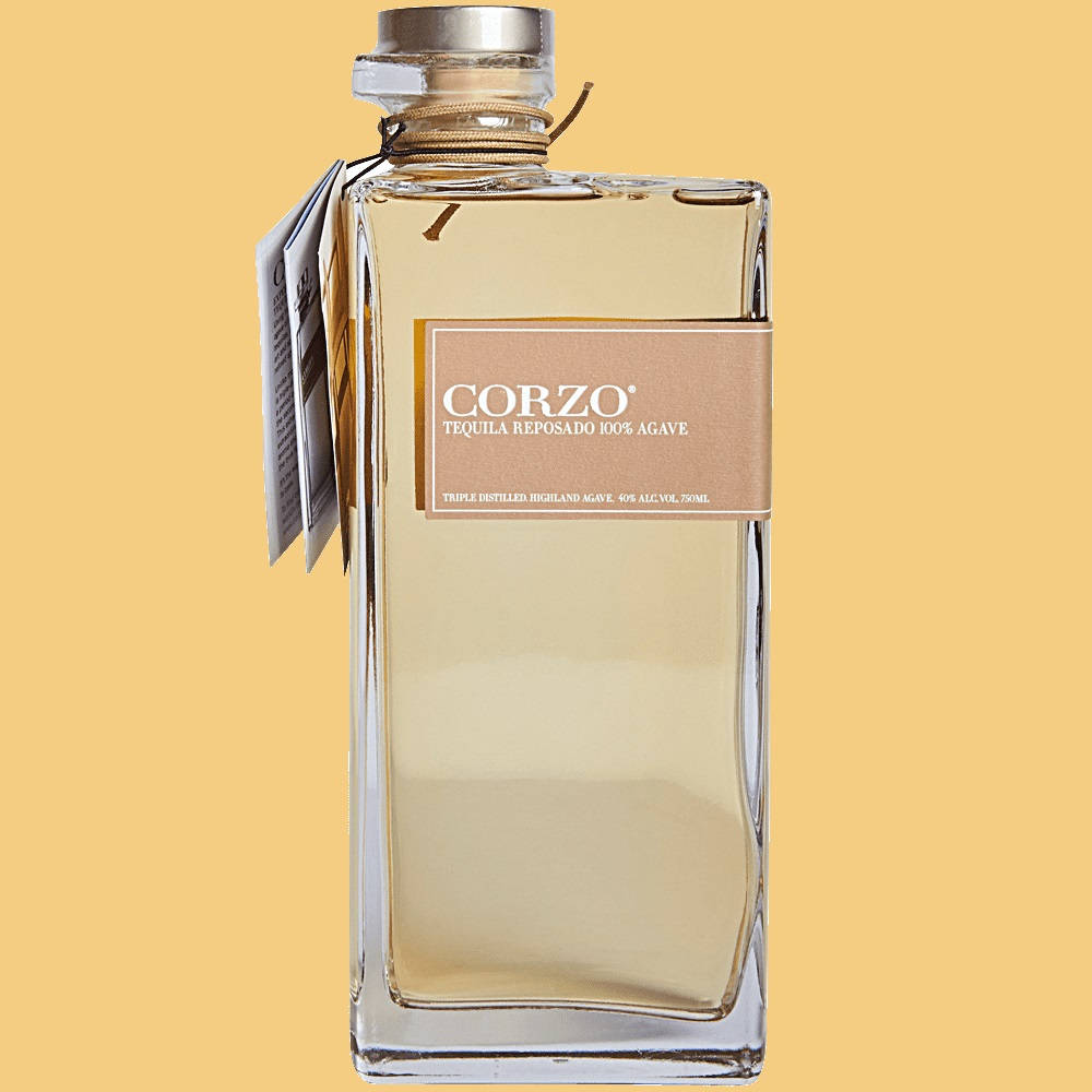 bottle 桌布 壁紙 — 一瓶透明的 Corzo Tequila Reposado 玻璃瓶，裝有金色液體和棕褐色標籤，立在純色暖黃色背景前。