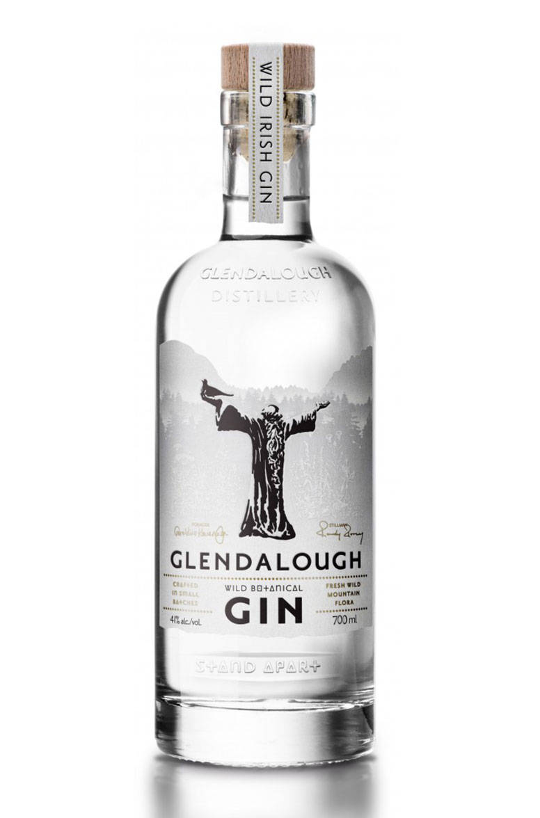 drinks 桌布 壁紙 — 一瓶透明的 Glendalough Wild Irish Gin 玻璃瓶，帶有木製軟木塞，標籤上印有黑色長袍人物剪影，背景為山脈。