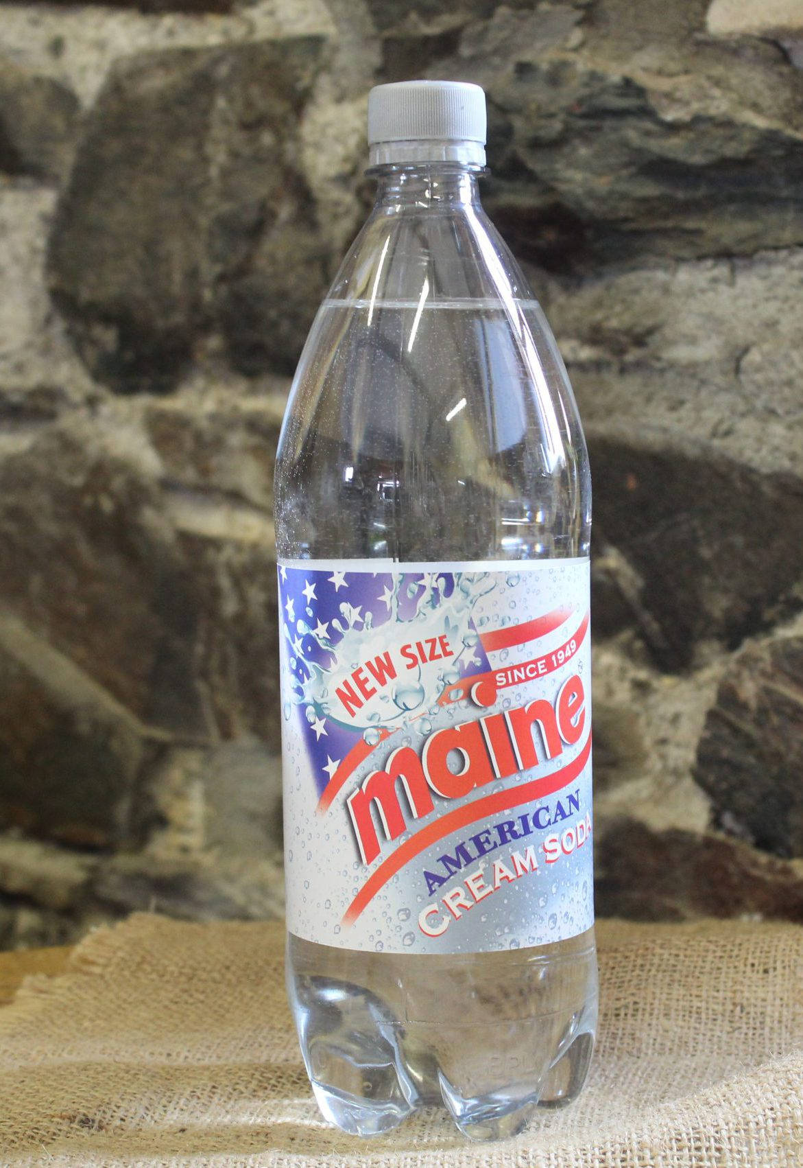 bottle 桌布 壁紙 — 一瓶透明的 Maine American Cream Soda 塑膠瓶放在粗麻布上，背景是粗糙的石牆。