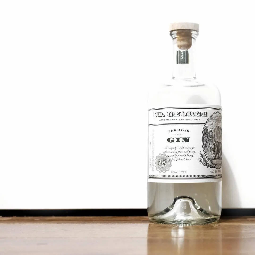 bottle 桌布 壁紙 — 一瓶透明的 St George Terroir Gin 配上軟木塞，放在木質表面上，背景是純白牆壁。
