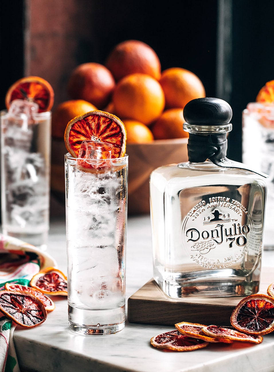 Fruits 桌布 壁紙 — 一瓶透明的Don Julio 70龍舌蘭酒旁邊放著一個裝滿冰塊的高腳杯，並以一片乾血橙裝飾。