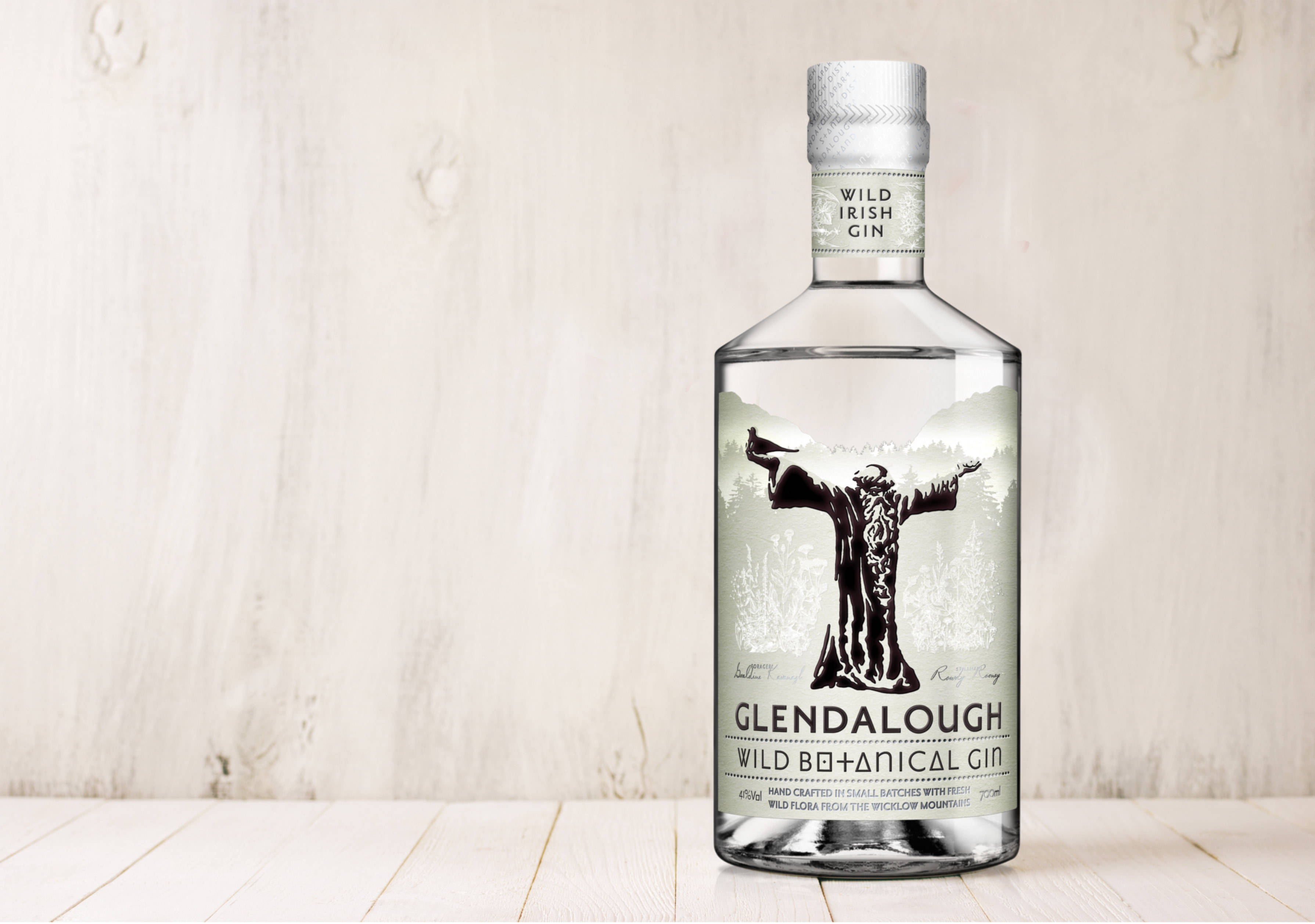 Gin 桌布 壁紙 — 一瓶透明的Glendalough Wild Botanical Gin酒瓶，置於淺色木質表面上，背景為相配的木質背景。