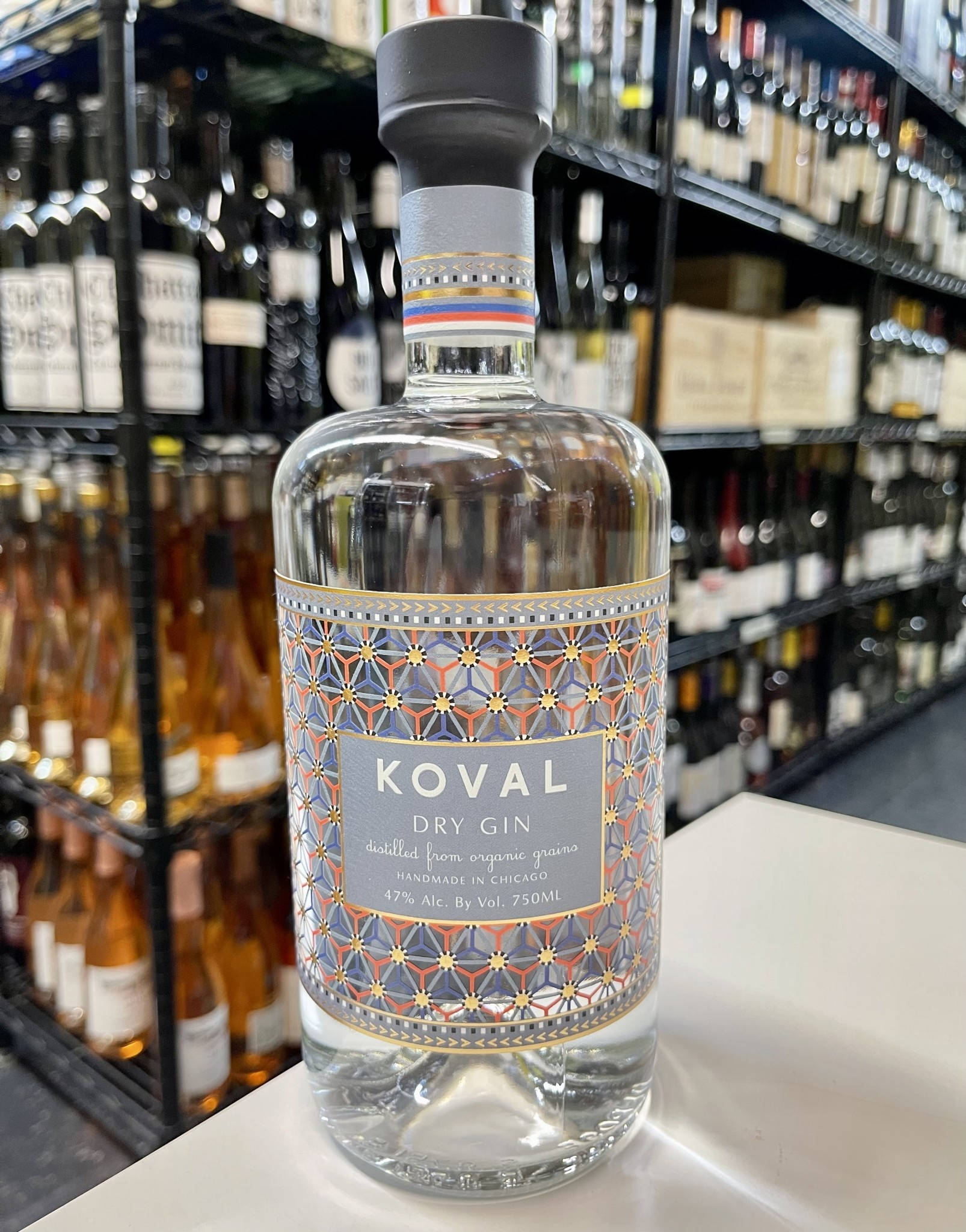 alcohol 桌布 壁紙 — 一瓶透明的Koval Dry Gin，帶有幾何標籤，放在一家貨品齊全的酒類商店的白色櫃檯上。