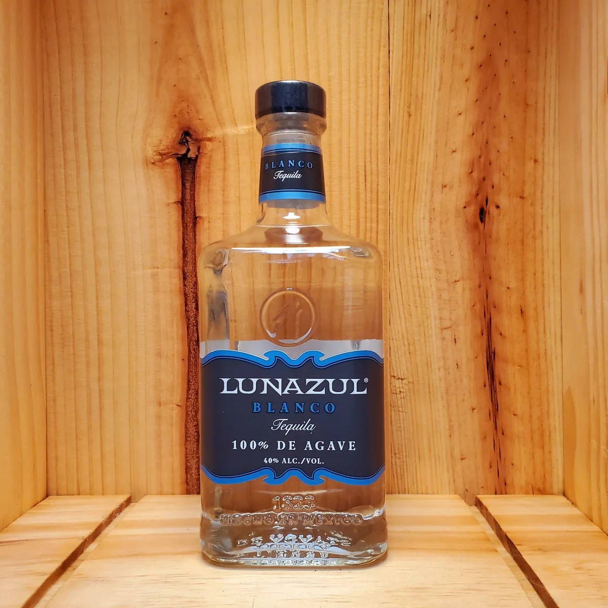 alcohol 桌布 壁紙 — 一瓶透明的Lunazul Blanco龍舌蘭酒，帶有藍色標籤，放在木架上，背景是溫暖的木鑲板。