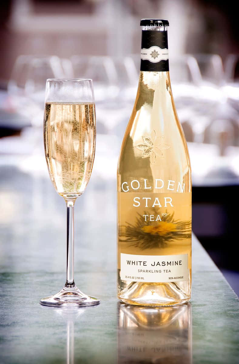 White Wine 桌布 壁紙 — 一瓶金白色茉莉花氣泡茶和一個裝滿的笛形杯優雅地放置在反射性檯面上，背景是柔和模糊的高級環境。