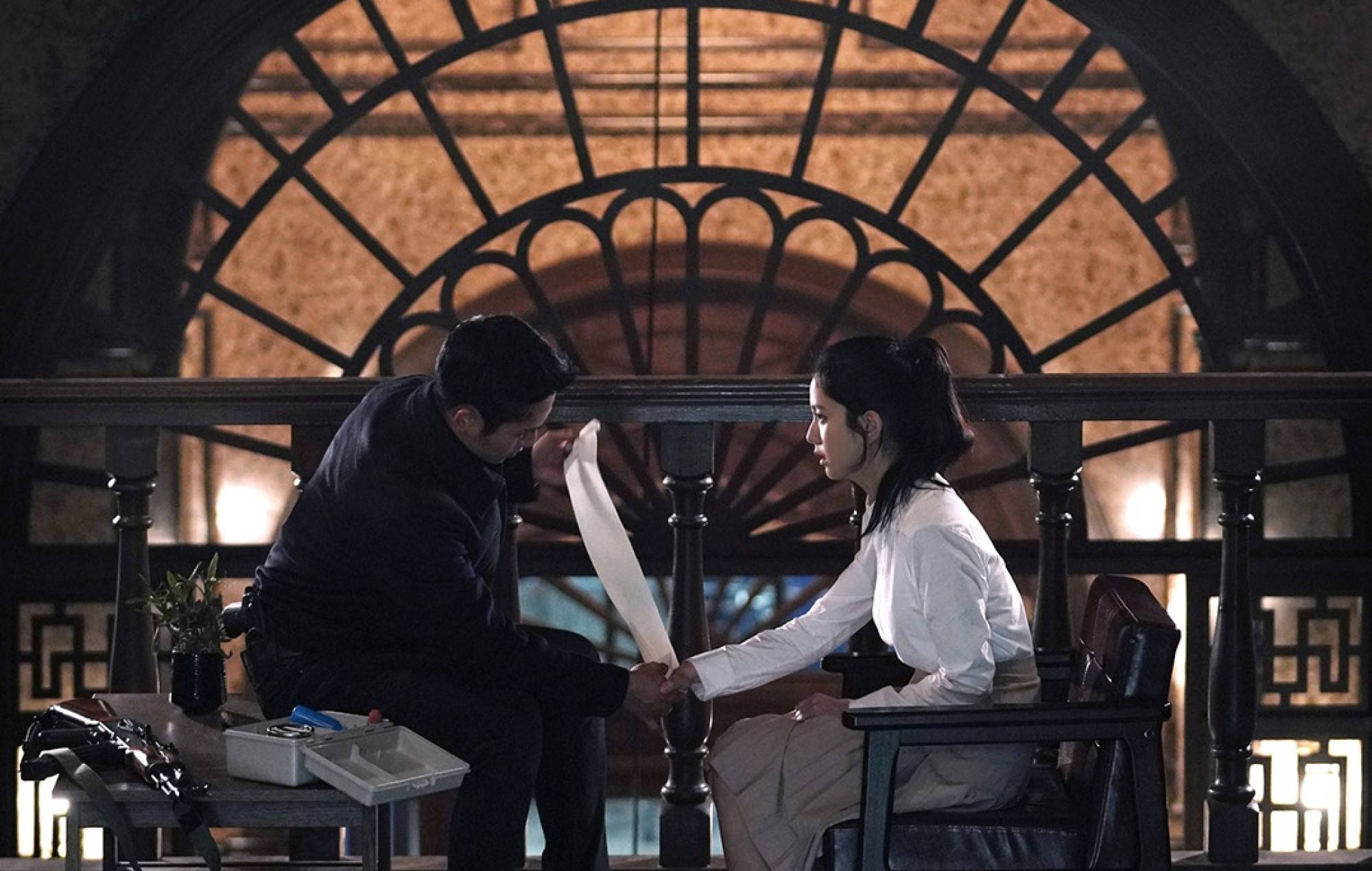 drama 桌布 壁紙 — 一男一女在昏暗的復古房間裡，在華麗的拱形窗戶下交換文件。