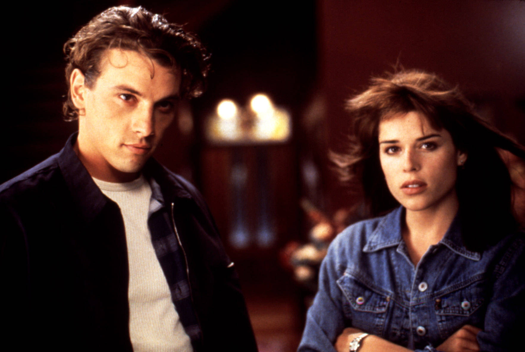 Billy Loomis 桌布 壁紙 — 一男一女在昏暗的房間裡專注地凝視，表情嚴肅，背景中溫暖的燭光柔和地閃爍。