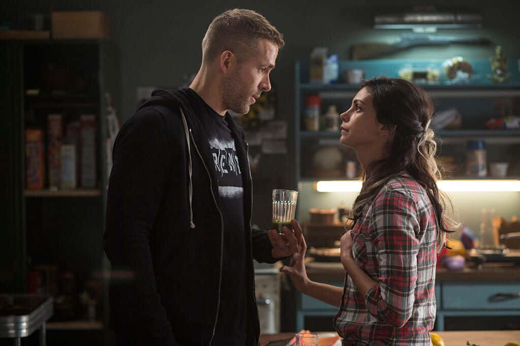 Deadpool And Vanessa 桌布 壁紙 — 一男一女在燈光昏暗的廚房裡面對面站著，一起拿著杯子，氣氛緊張。