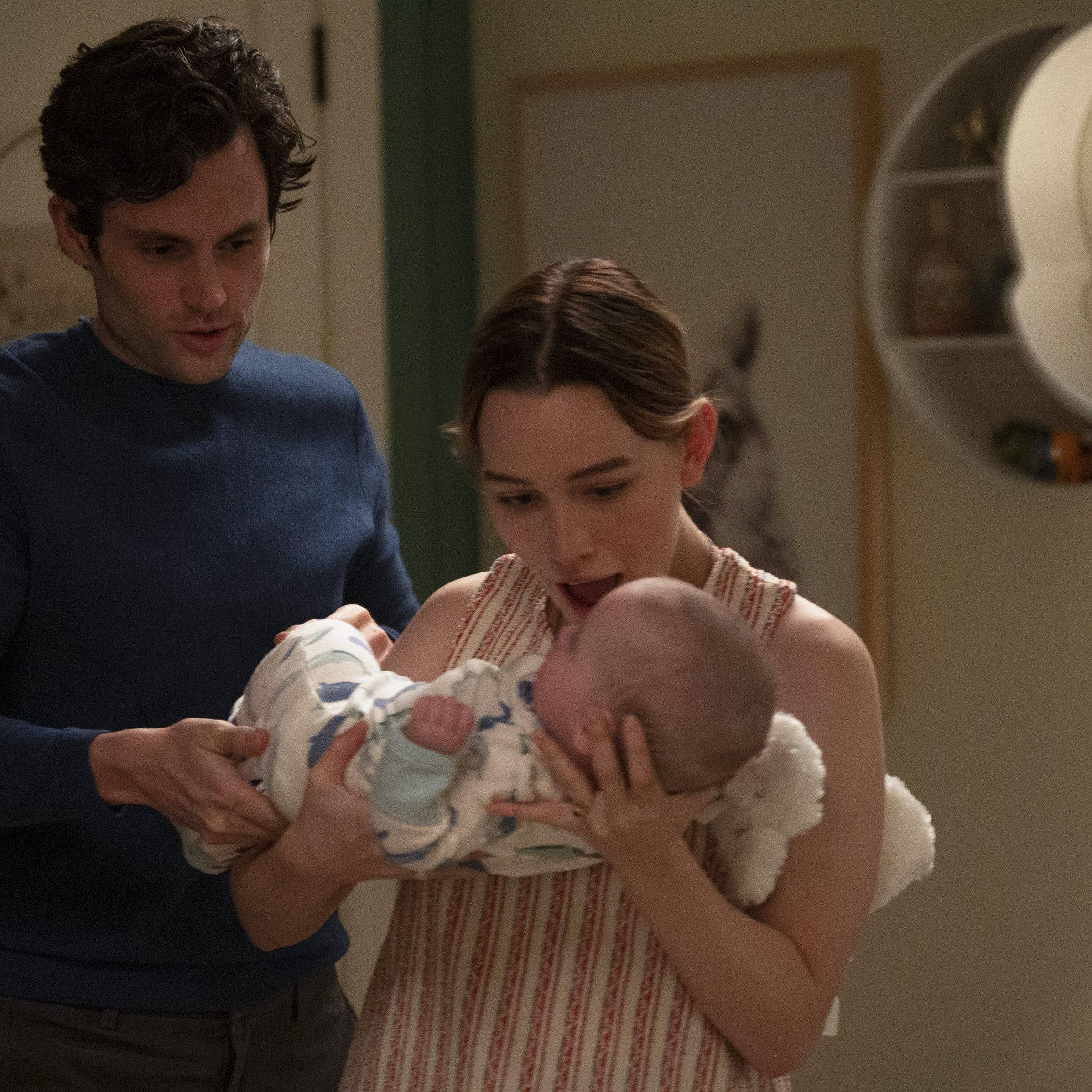 Netflix 桌布 壁紙 — 一男一女在燈光溫暖的房間裡，輕輕抱著一個裹著條紋毯子的新生嬰兒。