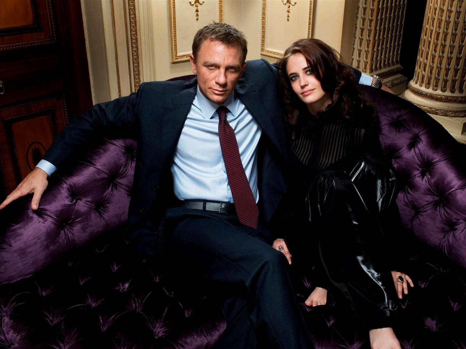 Daniel Craig 桌布 壁紙 — 一男一女在裝飾華麗的房間裡，親密地坐在一張豪華的紫色簇絨沙發上。