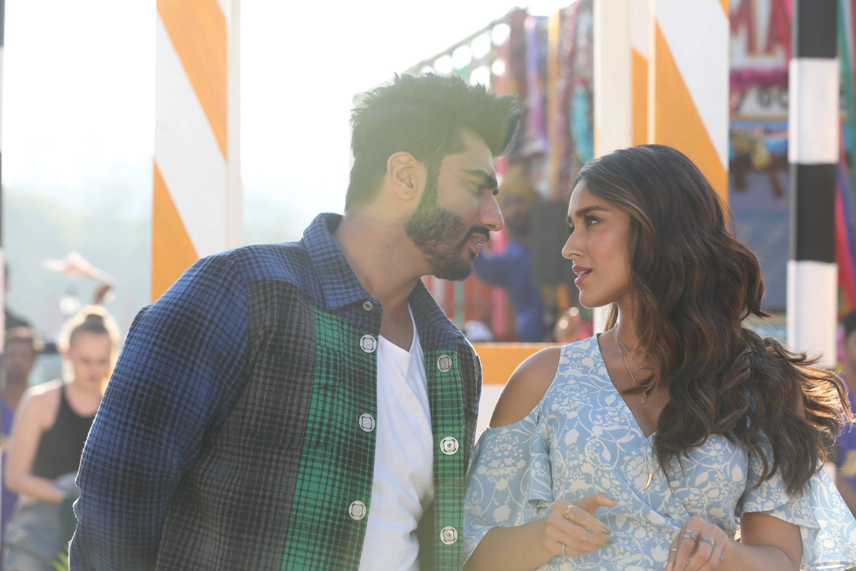Arjun Kapoor 桌布 壁紙 — 一男一女在陽光普照的嘉年華會上分享親密時刻，背景是色彩繽紛的條紋帳篷。