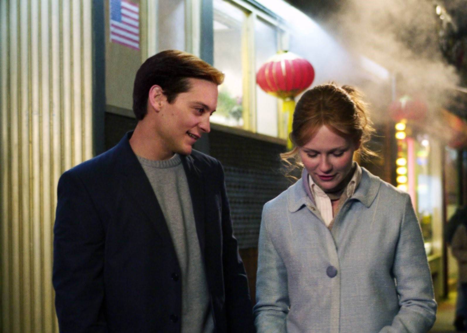 Spider Man 2 桌布 壁紙 — 一男一女夜晚一起走過煙霧瀰漫的唐人街，街道被紅色燈籠和溫暖的店鋪燈光照亮。