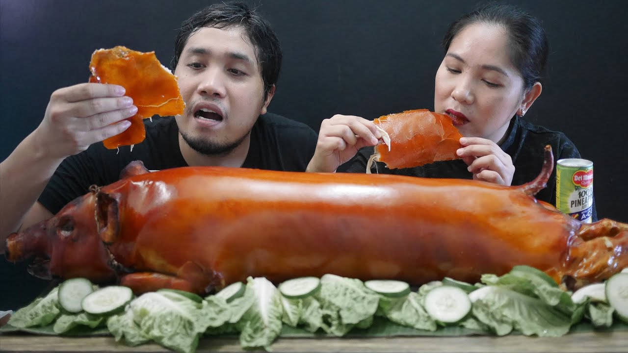 Pig 桌布 壁紙 — 一男一女急切地吃著脆皮烤豬皮，配以新鮮黃瓜和生菜裝飾。
