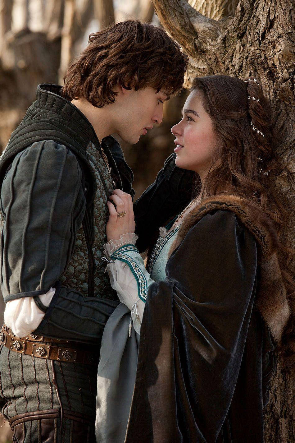 romeo and juliet 桌布 壁紙 — 一男一女穿著中世紀服裝，在陽光明媚的森林中一棵彎曲的樹旁分享親密時刻。