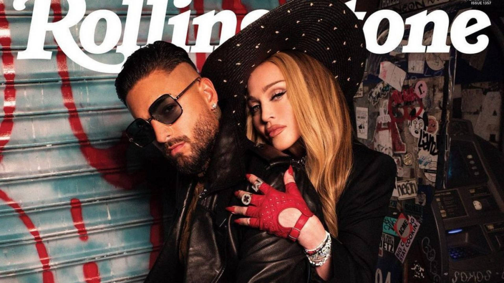 Maluma 桌布 壁紙 — 一男一女穿著皮革和紅色手套，在帶有 Rolling Stone 雜誌品牌的塗鴉金屬百葉窗前自信地擺姿勢。