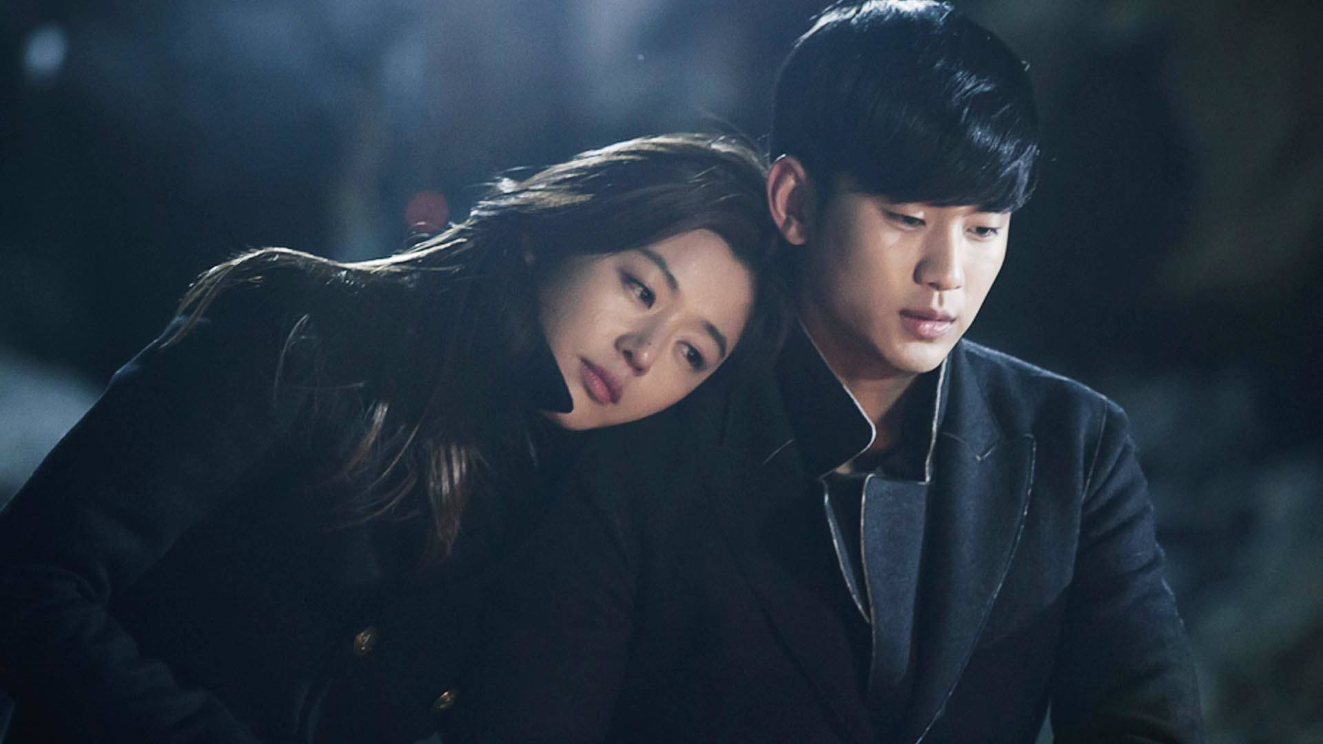 Jun Ji Hyun 桌布 壁紙 — 一男一女身穿深色大衣，在柔和的散景背景下，於陰鬱的夜間燈光下分享親密時刻。