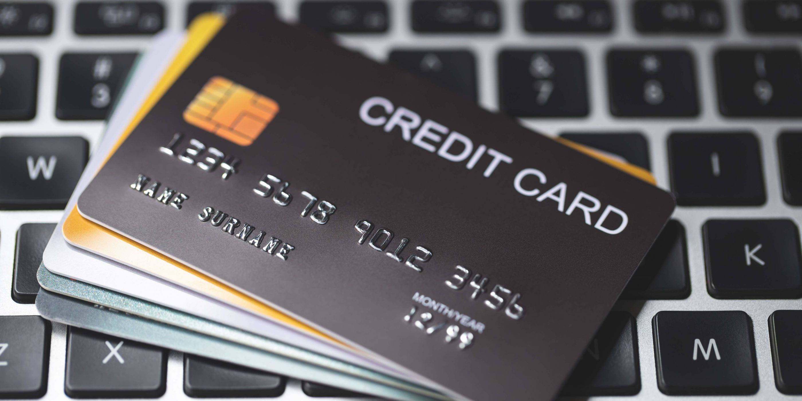 Credit Card 桌布 壁紙 — 一疊信用卡放在筆記型電腦鍵盤上，背景按鍵模糊。