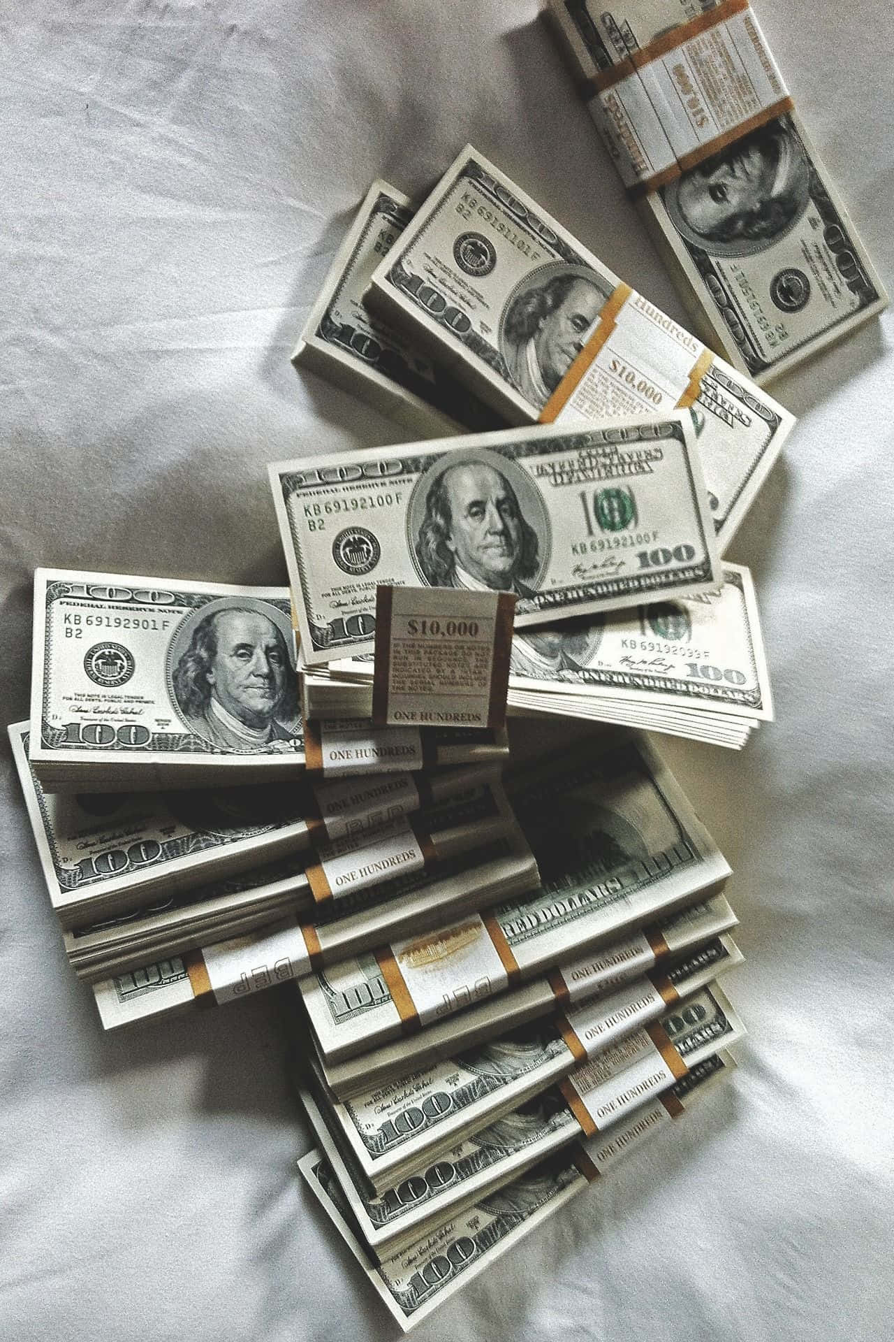 Rich 桌布 壁紙 — 一疊疊成捆的百元美鈔散落在柔和的自然光下的皺巴巴白色床單上。