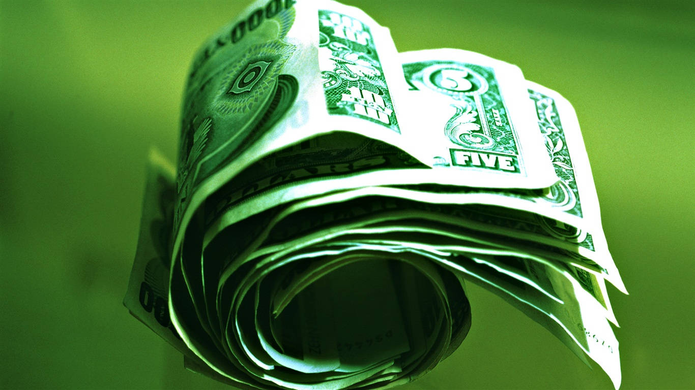 金錢 桌布 壁紙 — 一疊緊密捲起的美國五美元鈔票，在綠色色調的光線下發光，背景是模糊的綠色。