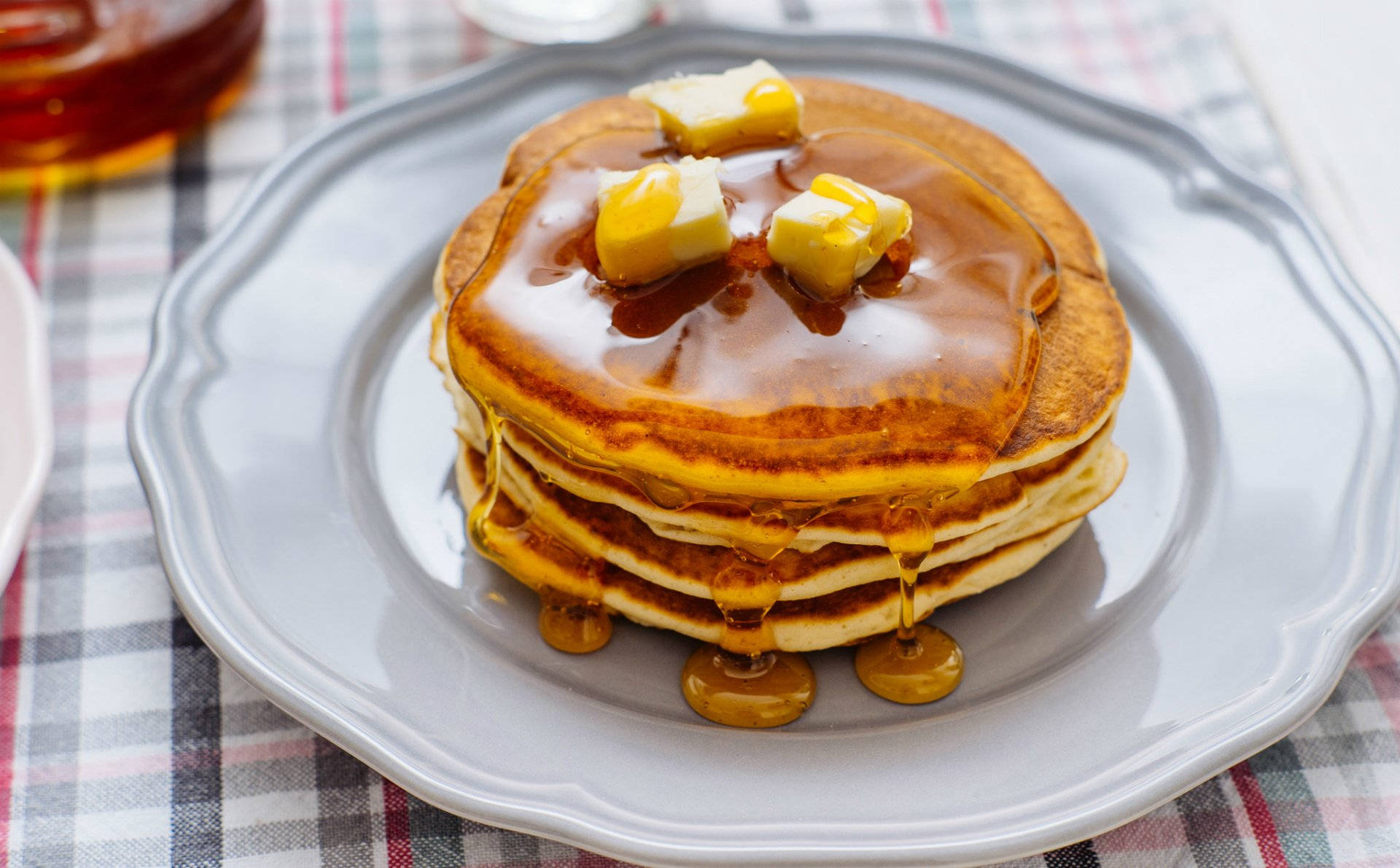 Pancakes 桌布 壁紙 — 一疊金黃色鬆餅，淋上糖漿，頂部有融化奶油，放在灰色盤子上。