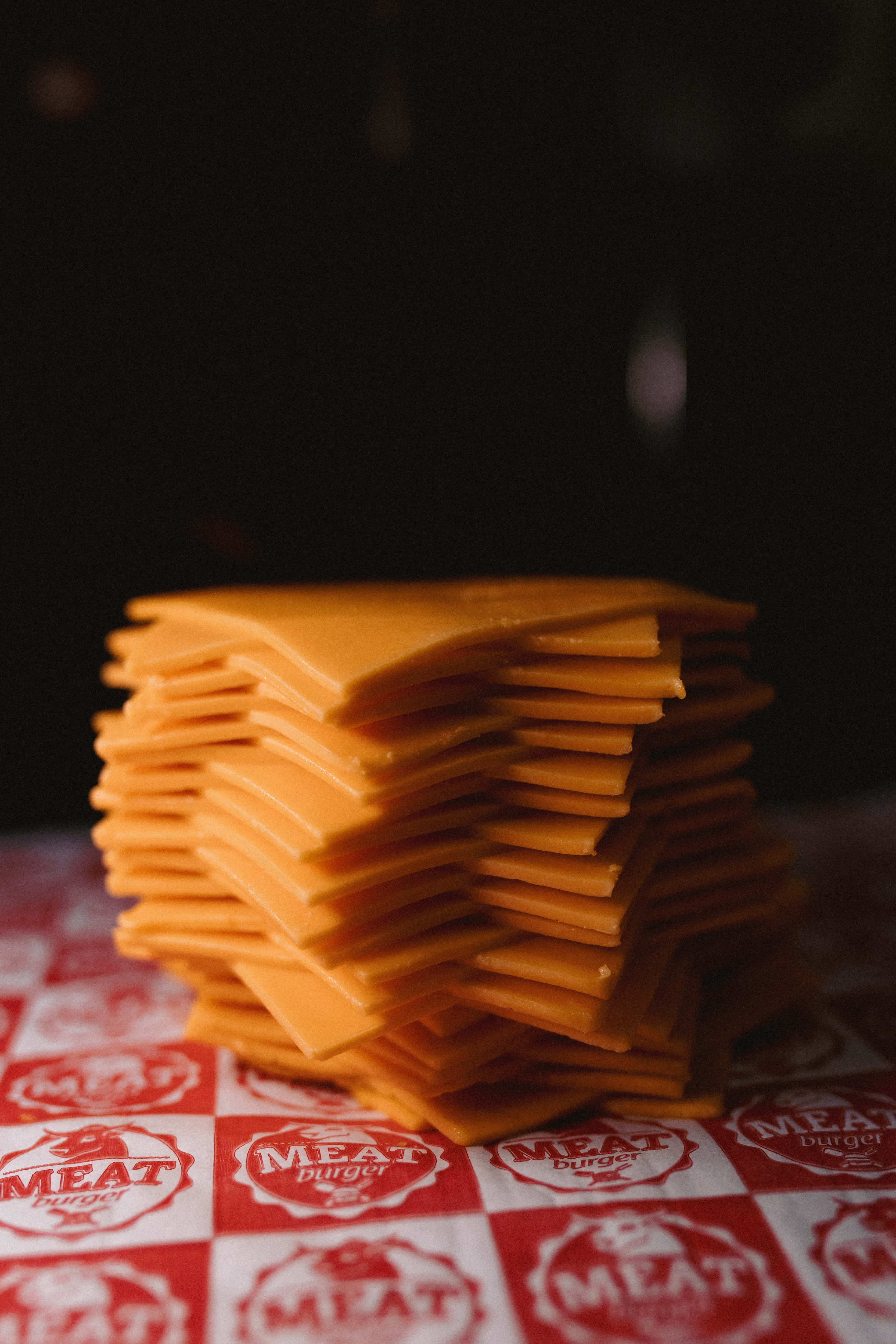 Cheese 桌布 壁紙 — 一疊高高的橙色起司片放在紅白格子 'MEAT burger' 紙上。
