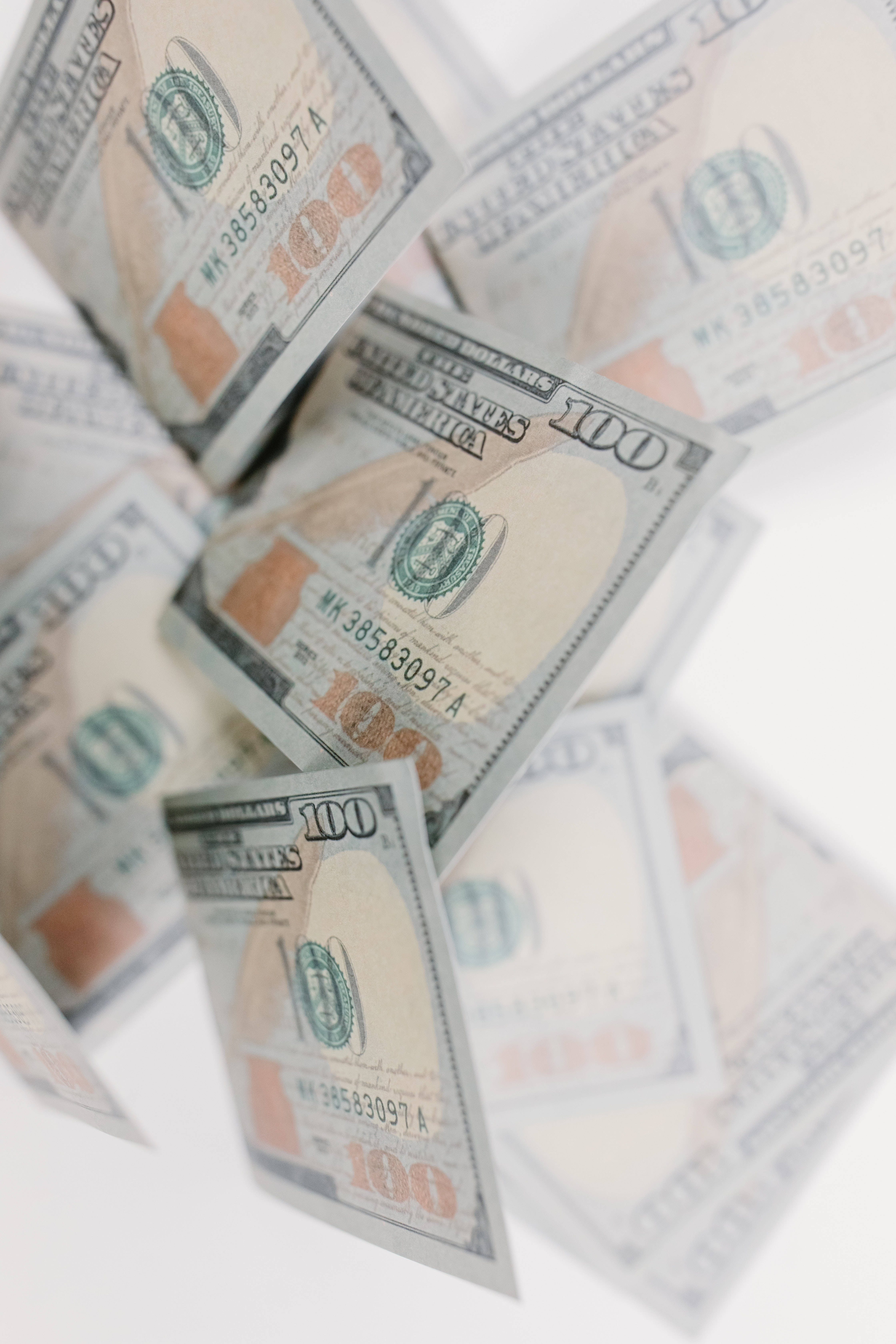 金錢 桌布 壁紙 — 一百美元鈔票在明亮的白色背景上以動態瀑布般漂浮和翻滾。