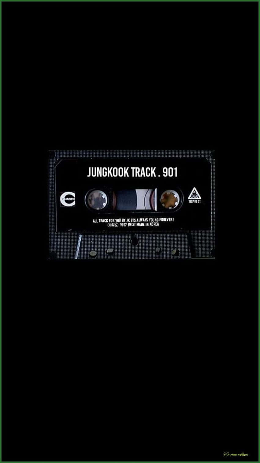 桌布 壁紙 — 一盒標有 'JUNGKOOK TRACK . 901' 的復古卡式錄音帶，在漆黑背景上隱約發光。
