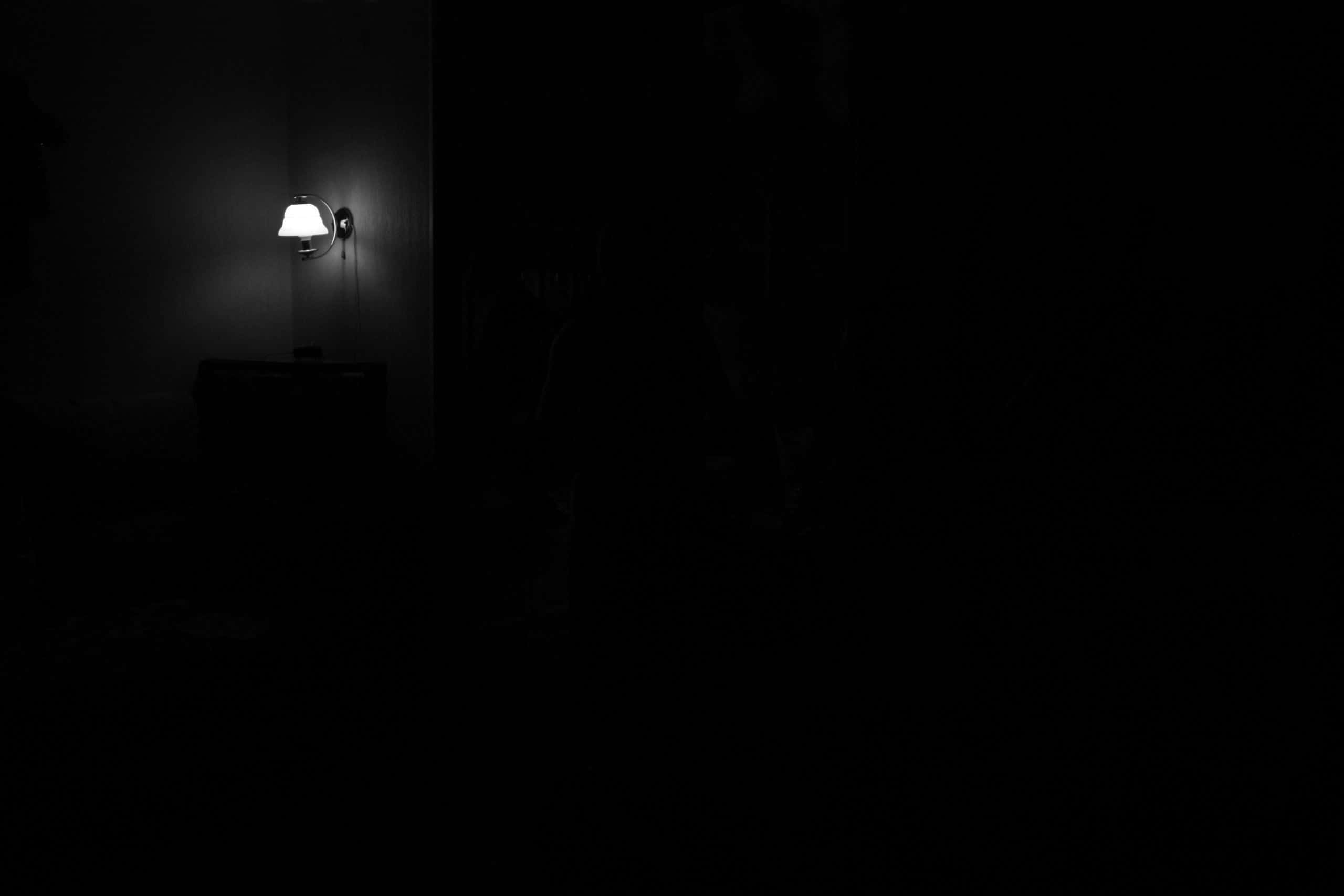 Dark Room 桌布 壁紙 — 一盞壁燈在漆黑的房間中發出柔和的光芒，營造出深邃的陰影。