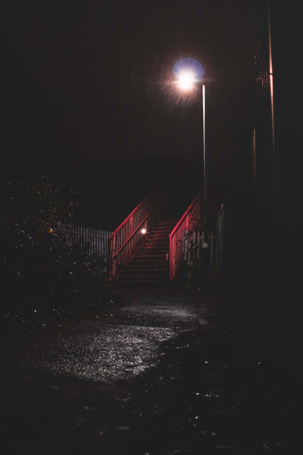 Night Time 桌布 壁紙 — 一盞孤獨的路燈在漆黑的夜空下，為濕漉漉的樓梯和欄杆投下溫暖的光芒。