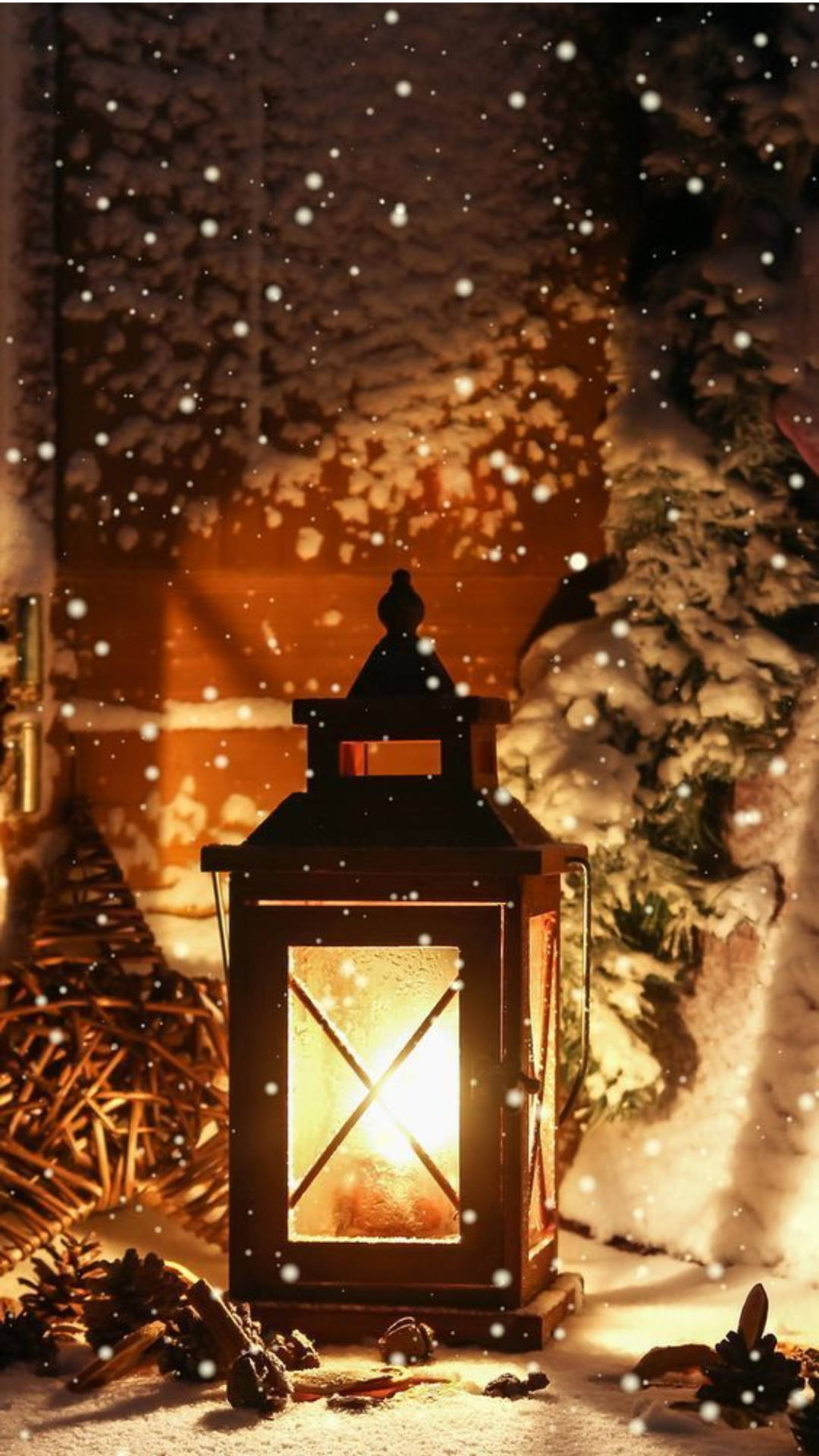 冬季 桌布 壁紙 — 一盞發光的燈籠在夜晚飄落的雪花中，將溫暖的光芒投射在積雪的松樹枝和松果上。