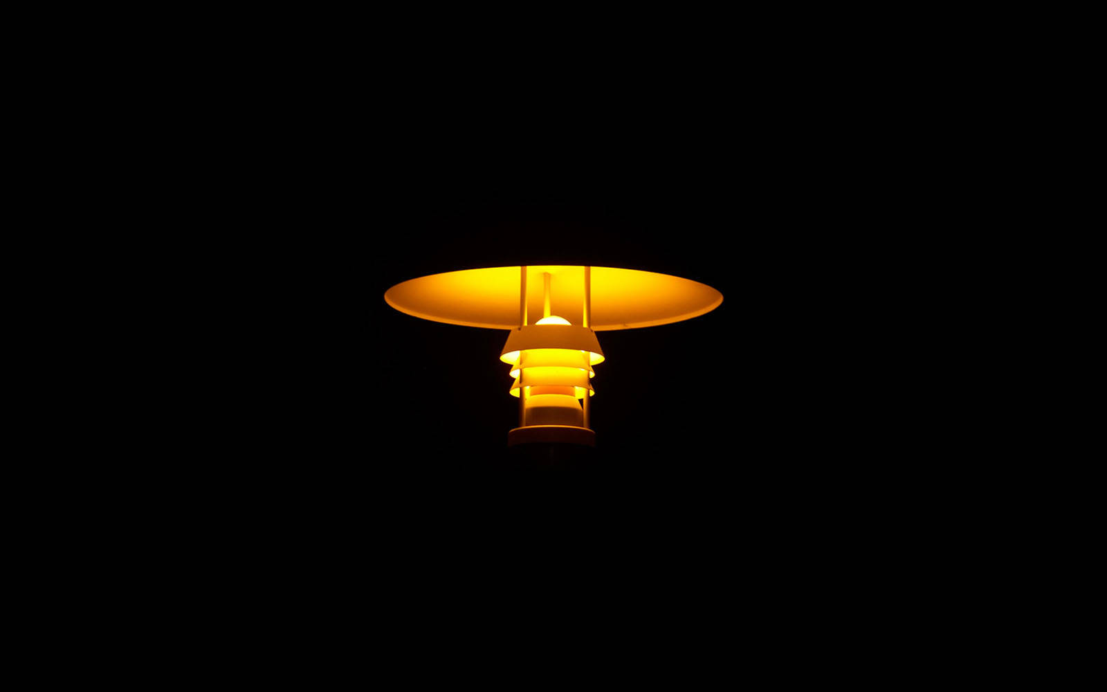 暗色電腦 桌布 壁紙 — 一盞發光的黃色街燈在漆黑的夜空中投射出溫暖的光芒。