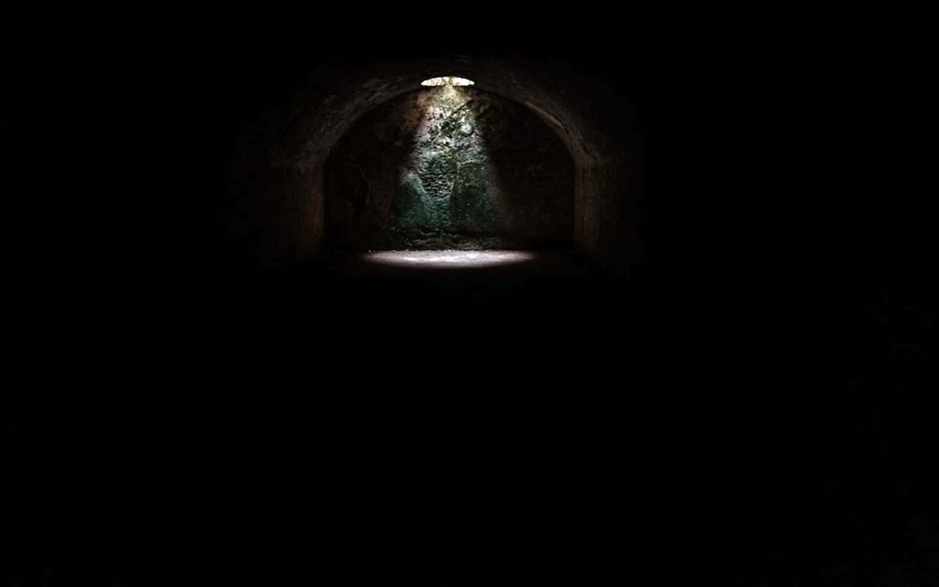 Spooky 桌布 壁紙 — 一盞聚光燈照亮了一條漆黑隧道中長滿青苔的石拱門。