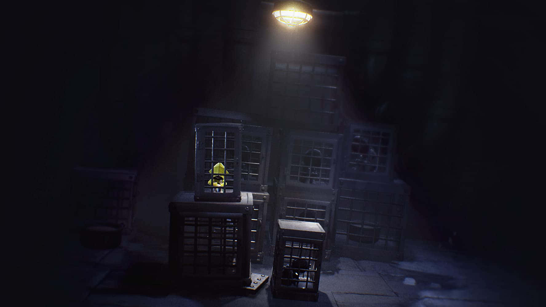 Little Nightmares 桌布 壁紙 — 一盞頭頂燈在黑暗廢棄倉庫中堆疊的金屬籠子上投下詭異的陰影。