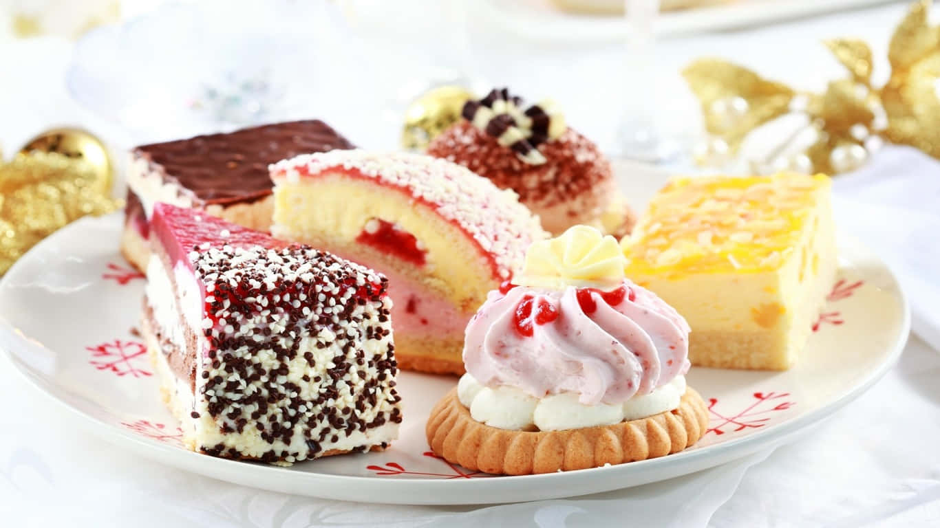 1366x768 Pastries 桌布 壁紙 — 一盤各式節日甜點，包括巧克力蛋糕、草莓卷和奶油泡芙，飾以金色節日裝飾。