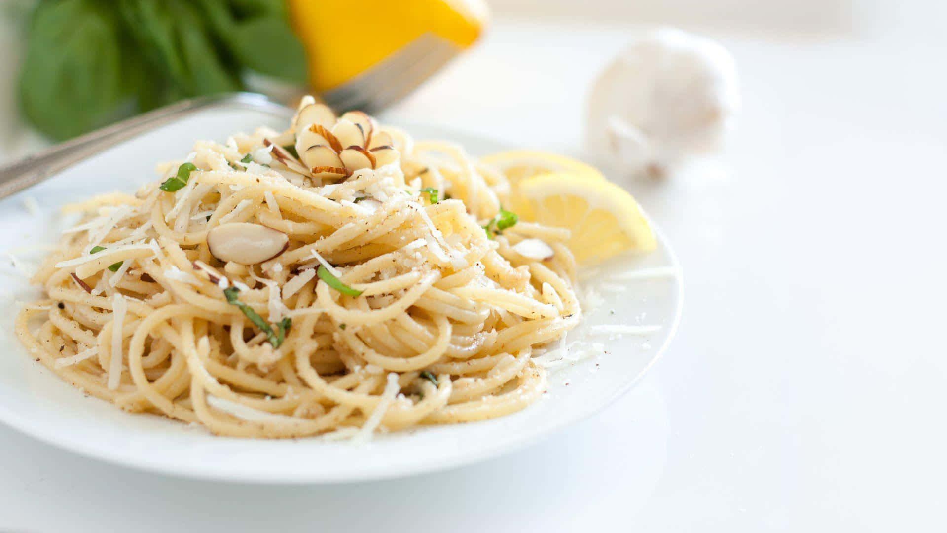 Pasta 桌布 壁紙 — 一盤奶油義大利麵，配上杏仁、檸檬片和新鮮香草，擺放在明亮的白色表面上，令人垂涎。