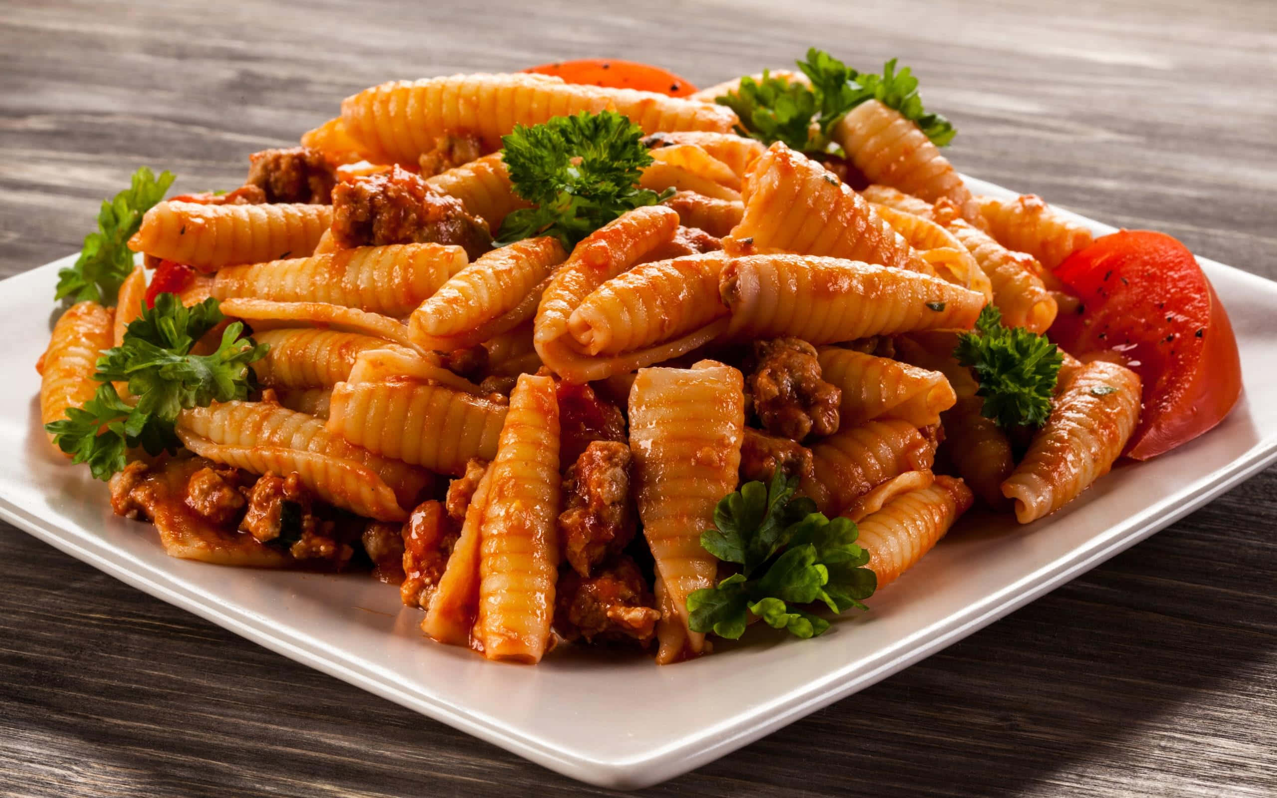 Pasta 桌布 壁紙 — 一盤奶油義大利麵搭配肉醬和新鮮歐芹裝飾，放在深色木桌上。