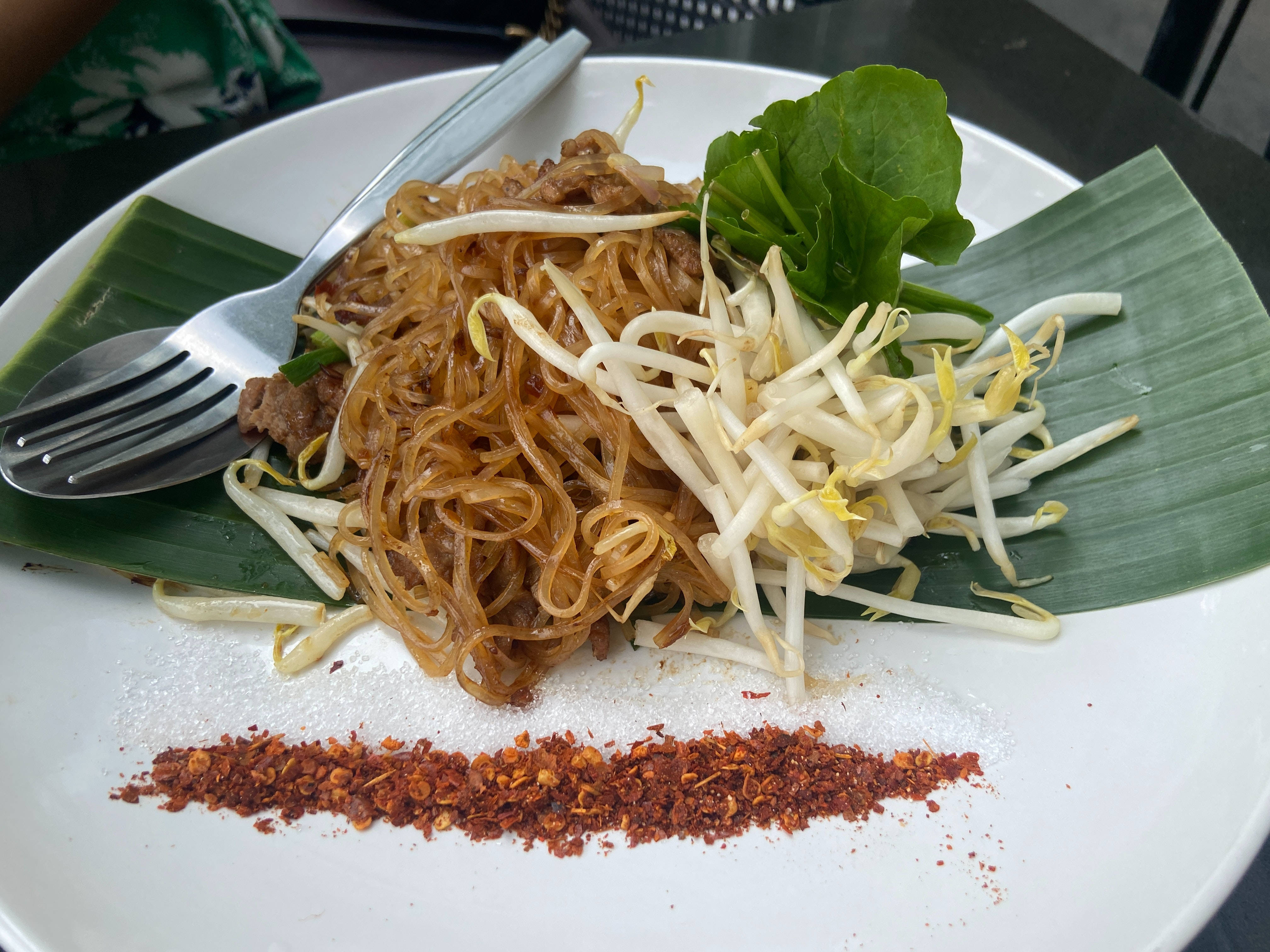 Delicious Food 桌布 壁紙 — 一盤炒米粉，上面放有豆芽和新鮮蔬菜，飾以辣椒片，並放在香蕉葉上享用。