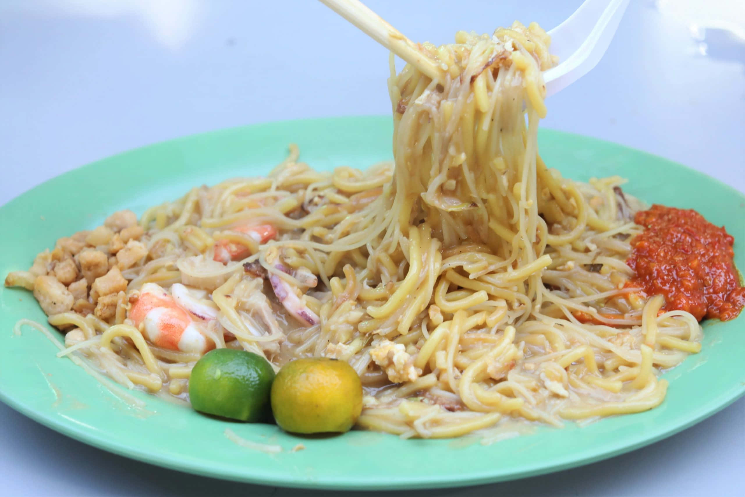 Noodles 桌布 壁紙 — 一盤炒麵搭配蝦仁、花生、辣椒醬和萊姆，用筷子夾起的特寫照片。