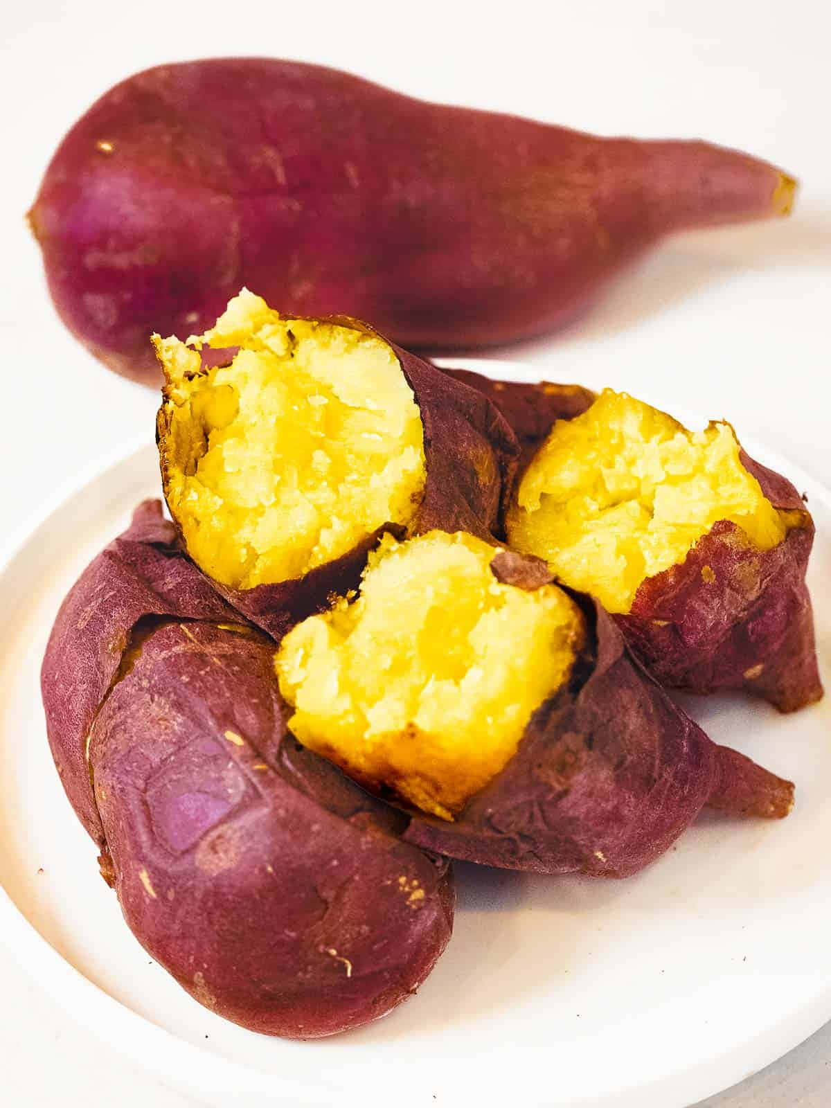 Yellow Sweet Potato 桌布 壁紙 — 一盤烤紫心番薯切開，露出蓬鬆金黃色的內部，襯托在潔白的背景上。