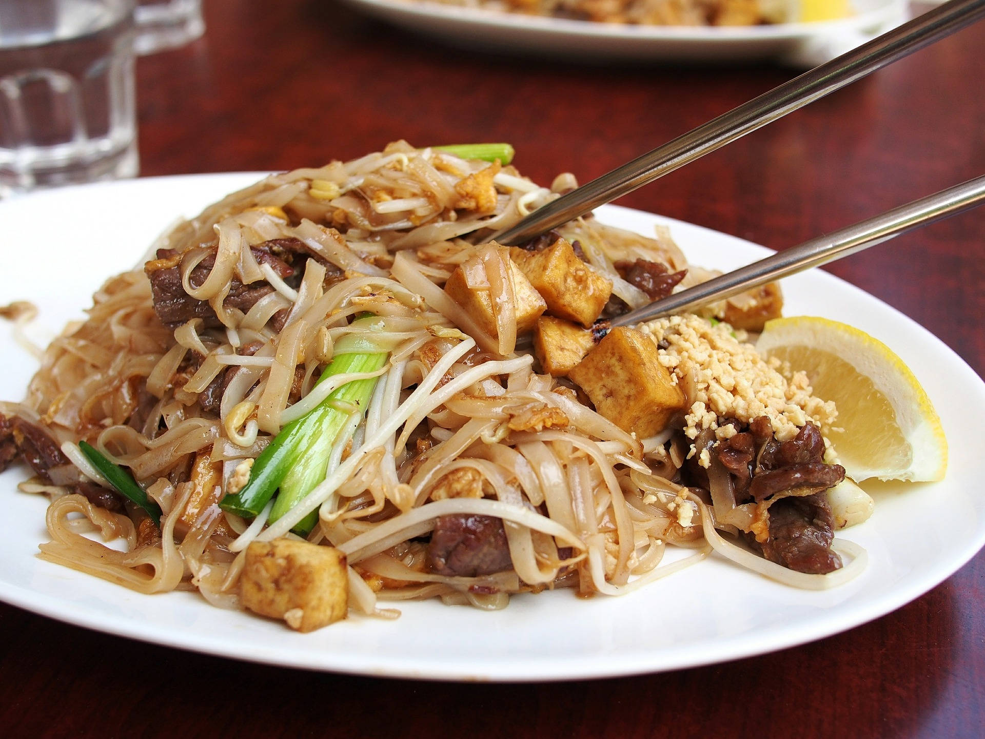tofu 桌布 壁紙 — 一盤熱騰騰的炒米粉，搭配豆腐、牛肉、豆芽和萊姆裝飾。